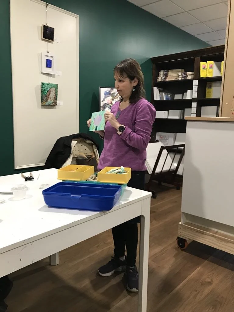 Woman standing up and presenting a piece of artwork in an art studio