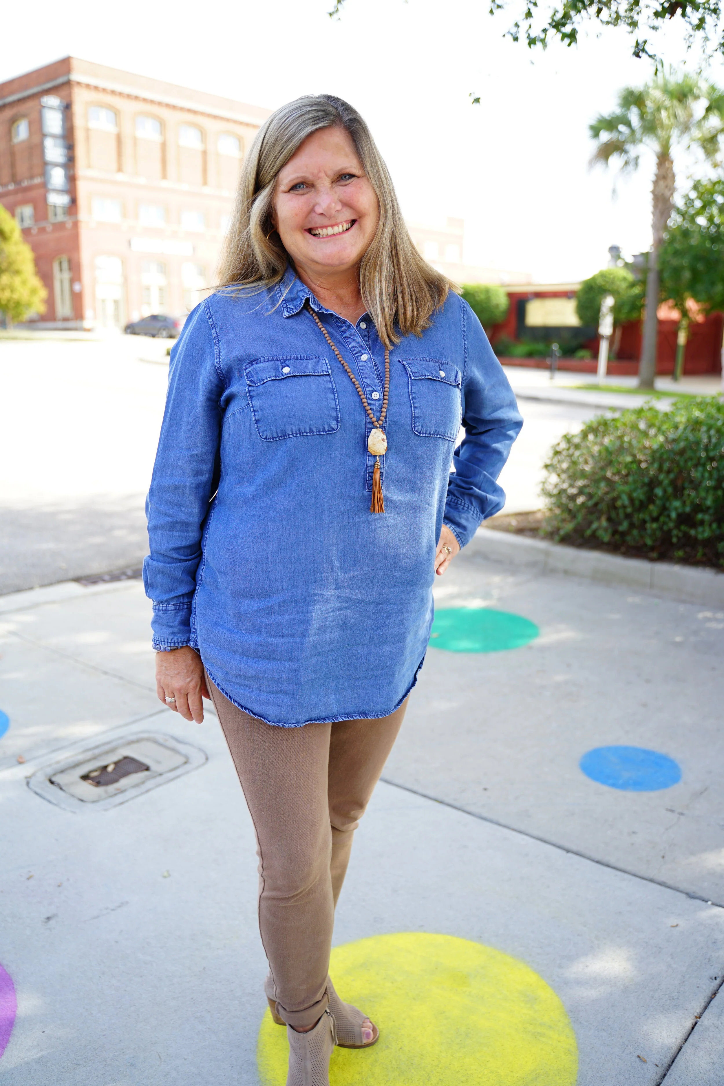 A woman standing in an empty parking lot, with one hand on her hip.