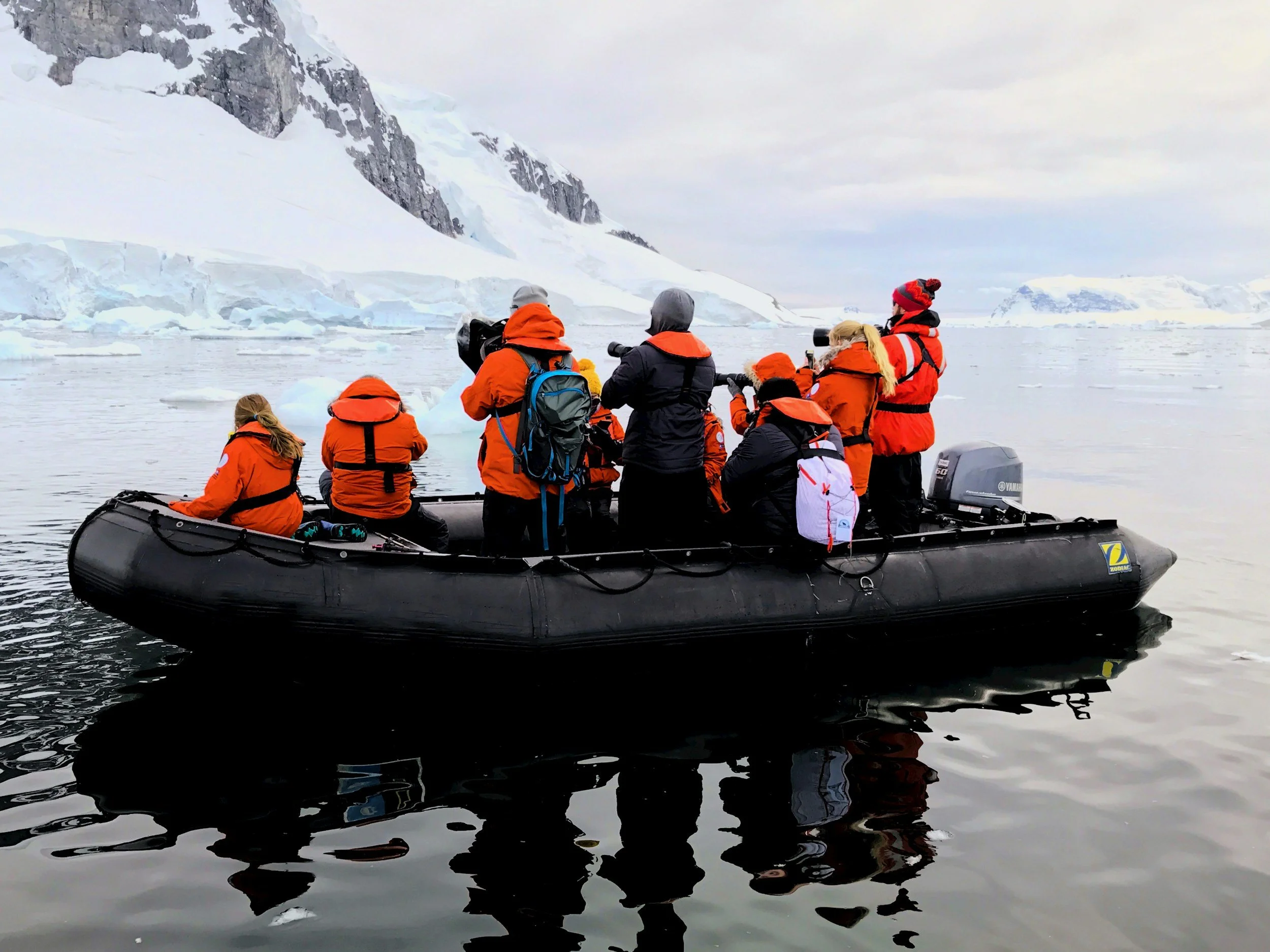 People aboard a Zodiac boat exploring the Antarctic landscape together on an adventure-focused family-travel experience.