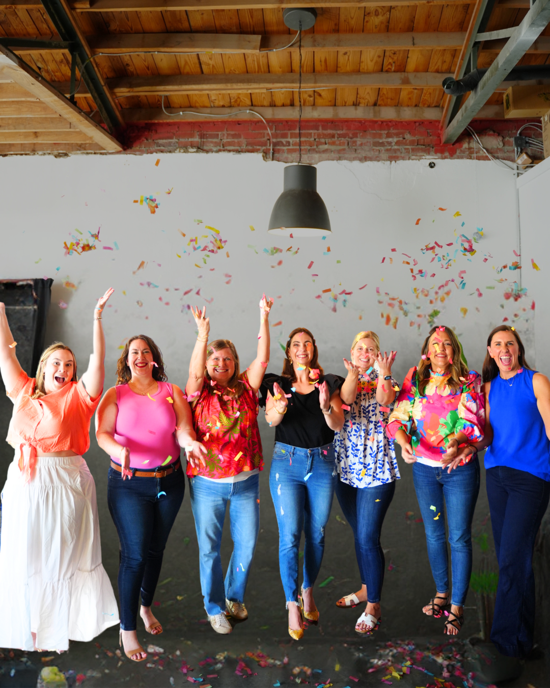 7 People throw confetti into the air, in an indoor studio environment.