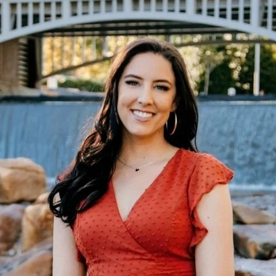 A person in a red dress, sitting down in an outdoor setting.