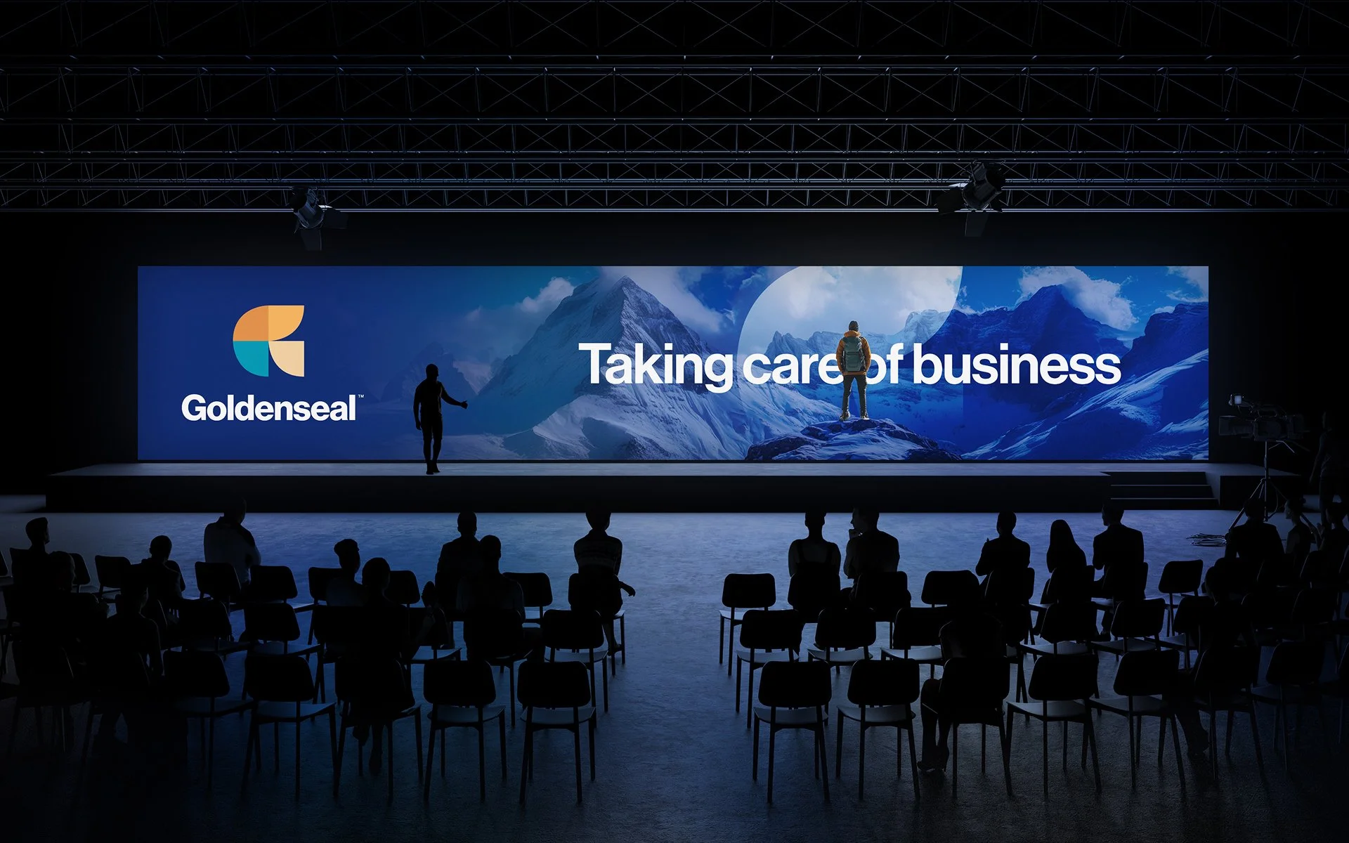 Goldenseal event stage branding with large screen display and audience, featuring “Taking care of business” message