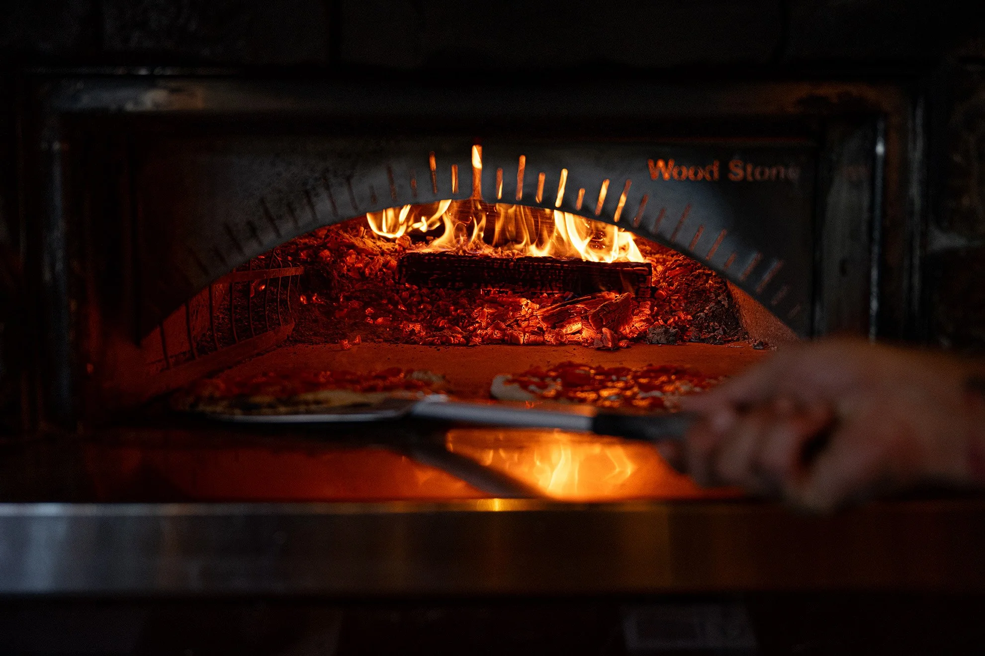  A look into the wood-fired oven at James Beard Award nominated East Nashville restaurant, Lockeland Table. The pizza chef is using a large paddle to place a pizza close—but not too close—to the flame. 