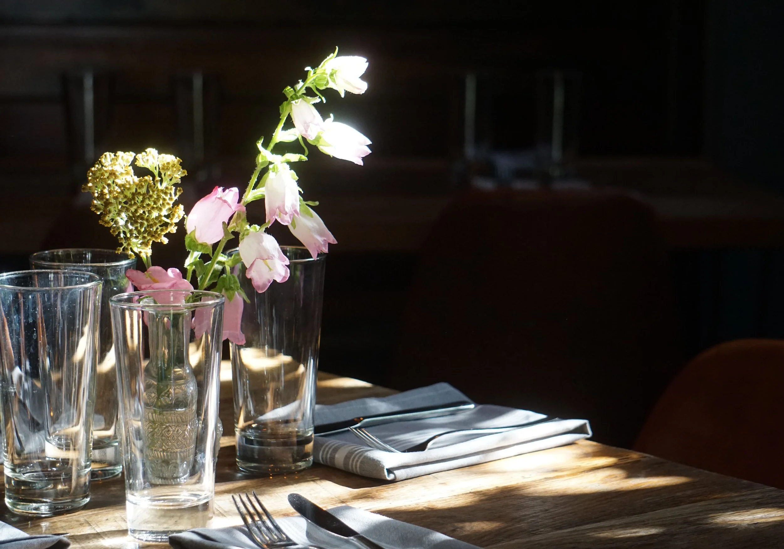  The sunlight shining through a glass vase that contains flowers at a table at James Beard Award nominated East Nashville restaurant, Lockeland Table. 