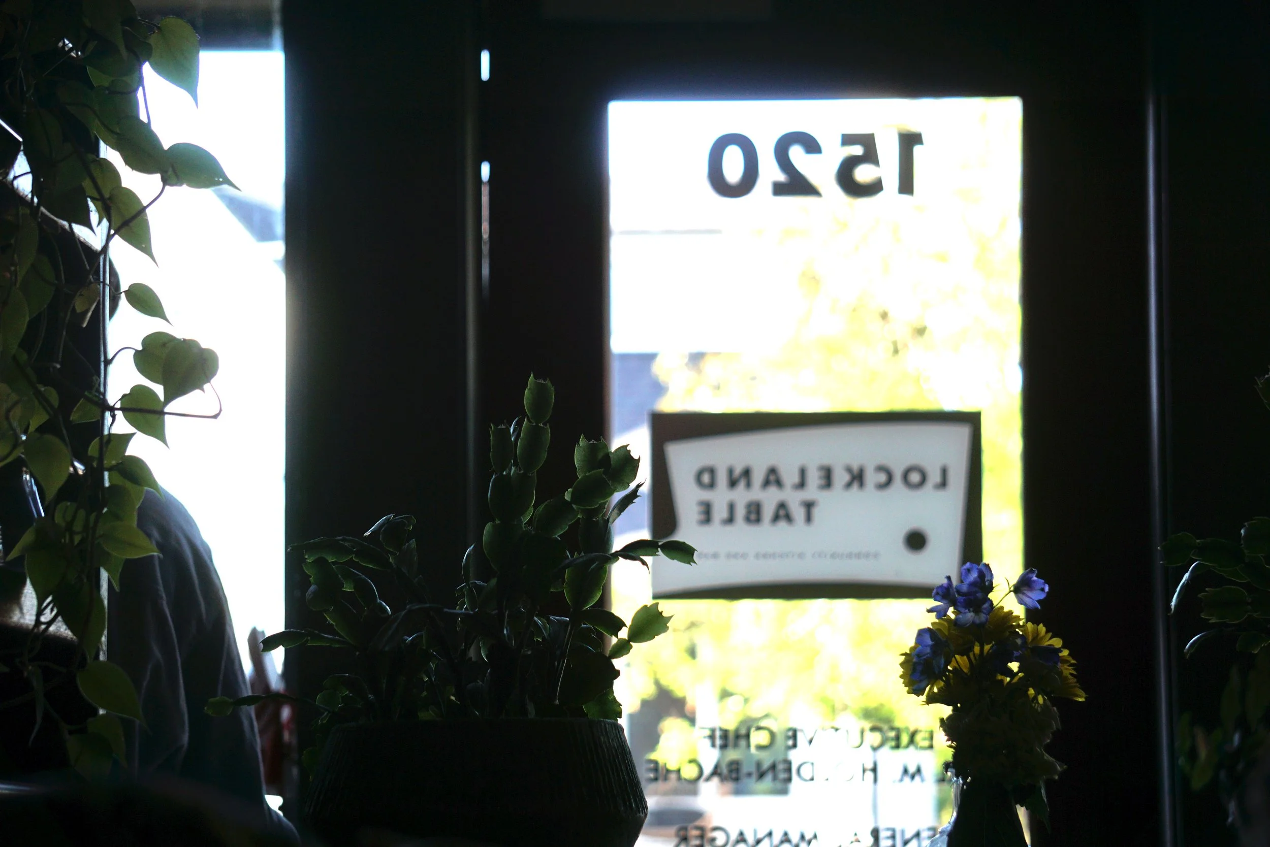  A shot from inside James Beard Award nominated East Nashville restaurant, Lockeland Table, looking out through the glass door. The Lockeland Table logo is on the door but appears reversed here because the shot is from inside the building. 