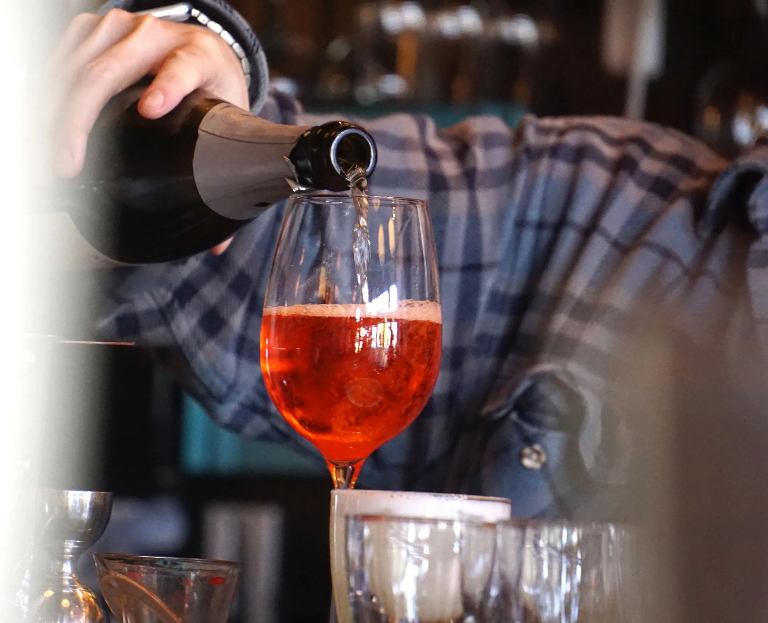  A bartender pouring a glass of sparkling wine at James Beard Award nominated East Nashville restaurant, Lockeland Table, likely for Community Hour—our community-focused version of Happy Hour. 