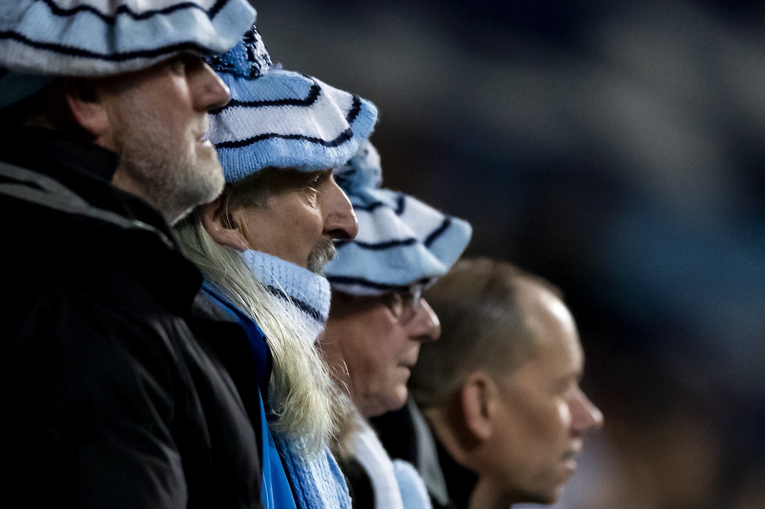 People in blue and white striped hats focused on something off-camera.