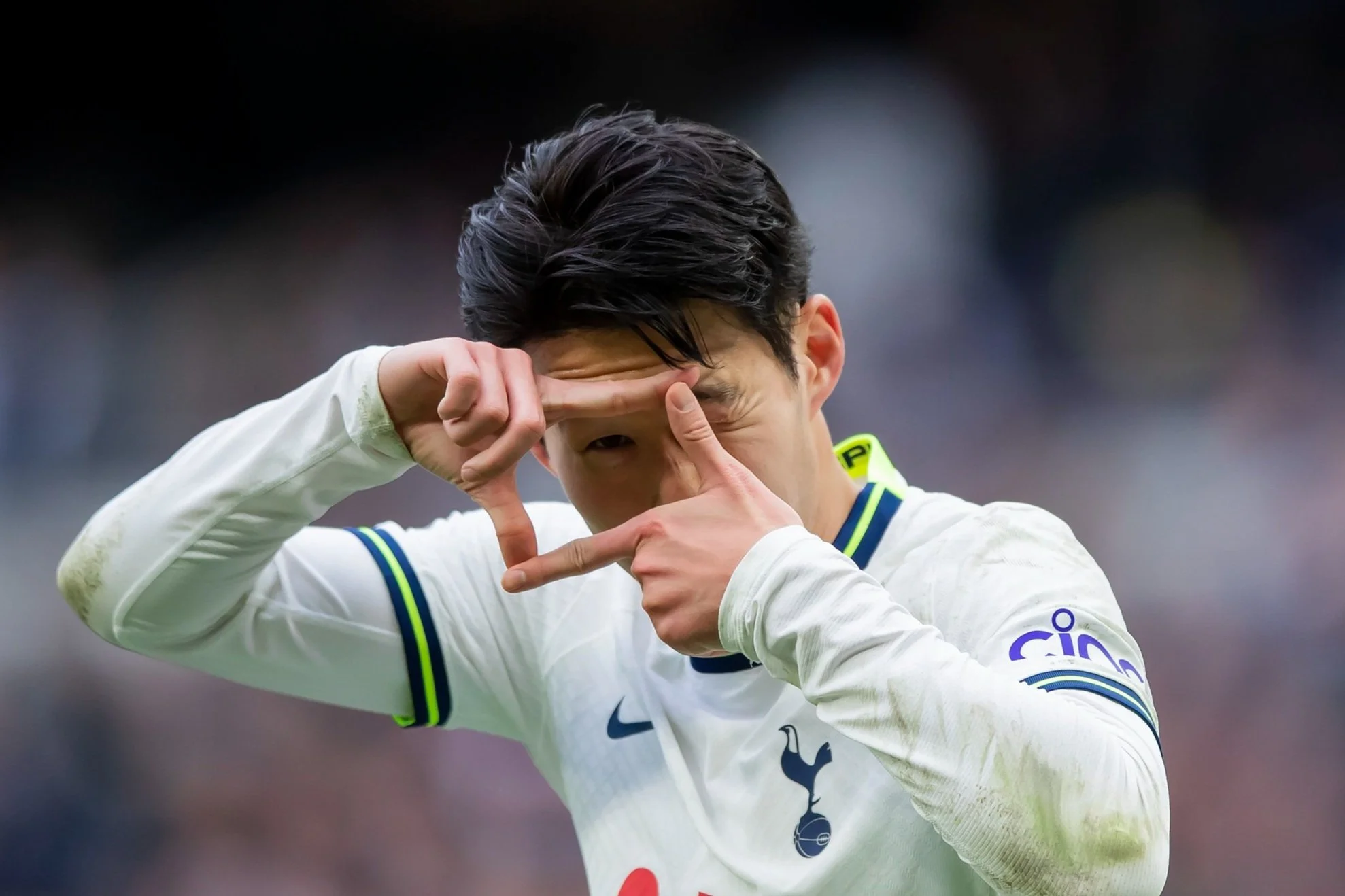 Soccer player in a white jersey forming a rectangle with hands over face.