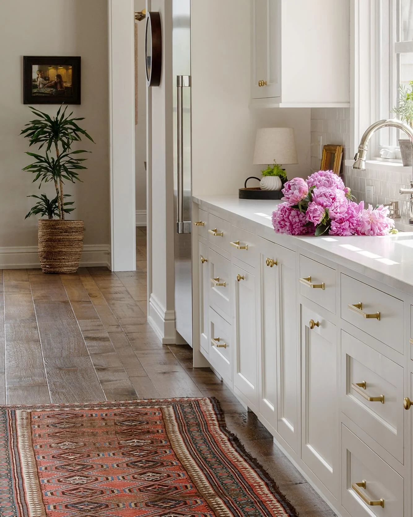 My favorite time of year - Peony  Season! 
Design: @interiorbloomsdesign 
📷: @laraparentphotography 
Build: @bouwkampbuilders 

Brass hardware detail, warm white cabinets, vintage rug style, warm neutral kitchen, sink full of flowers, kitchen sink w