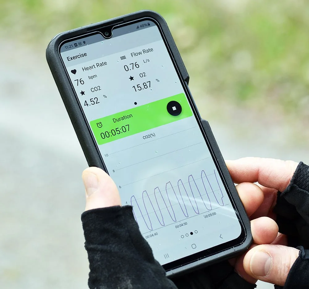 Close-up of a mobile phone screen displaying a heart rate monitor app outdoors.