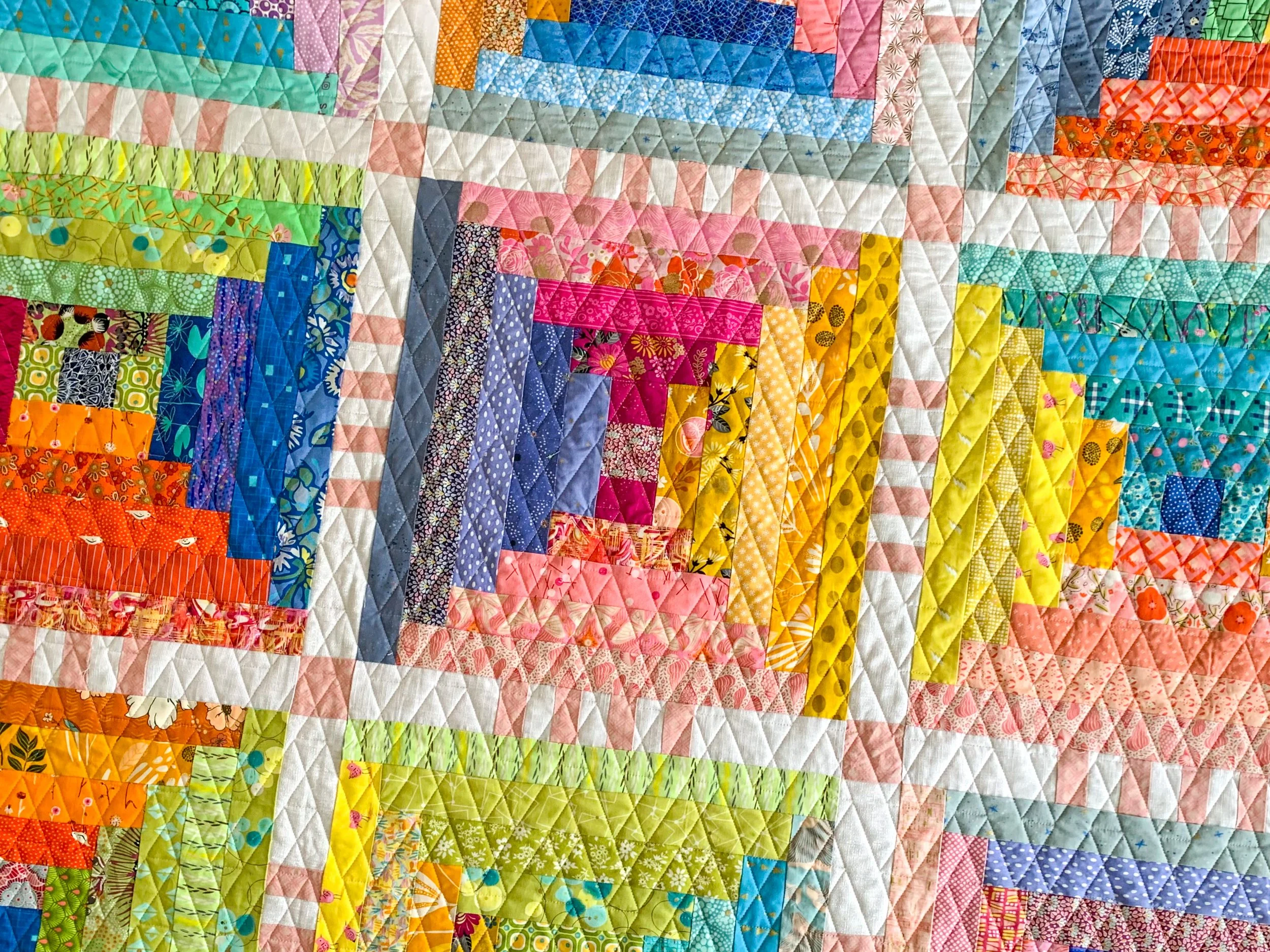 flat front image of courthouse steps quilt in rainbow fabrics and dense geometric quilting
