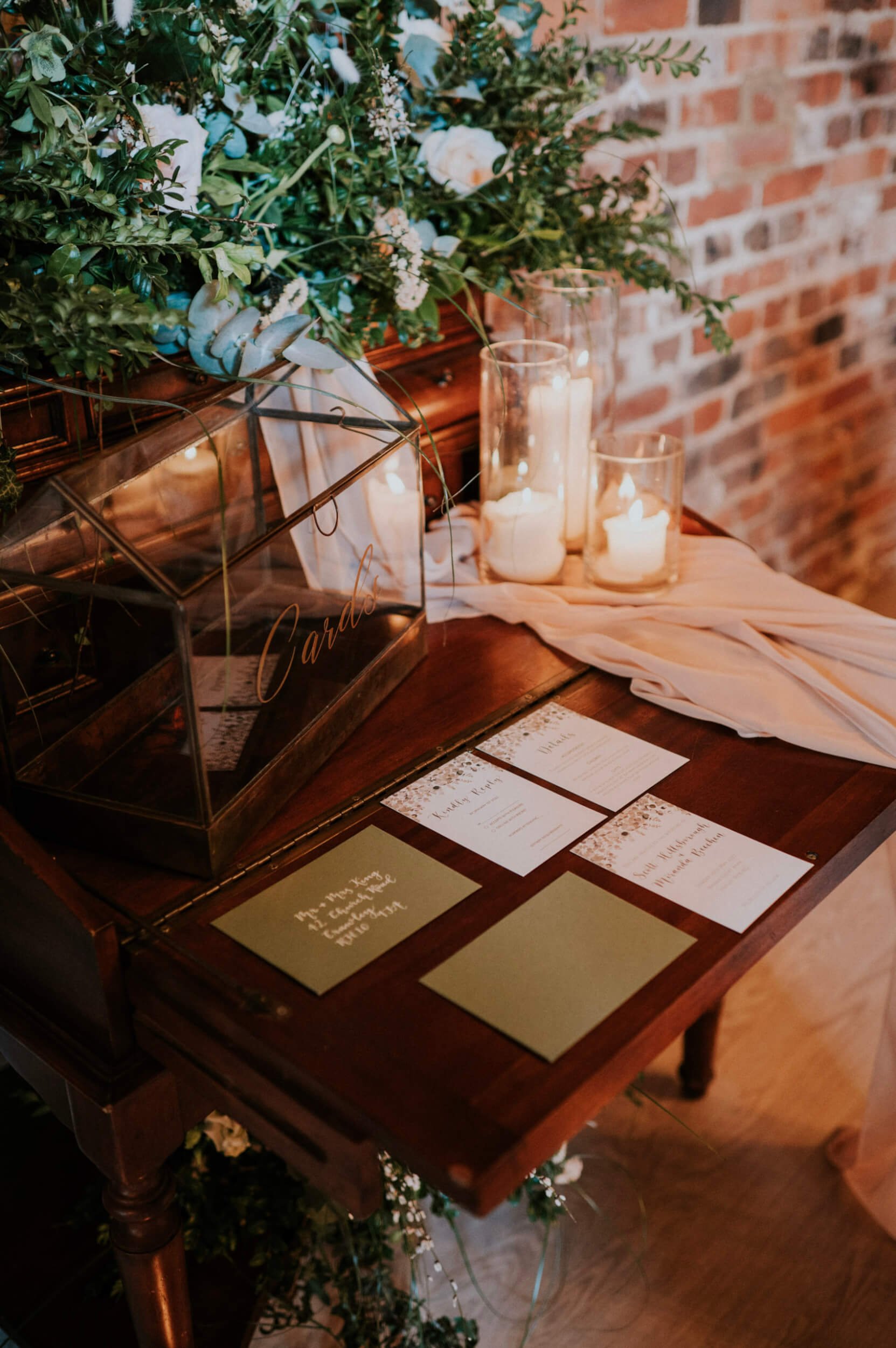 Antique Bureau decorated with greenery, white flowers, candles, and wedding stationery, available to hire for your wedding or event.