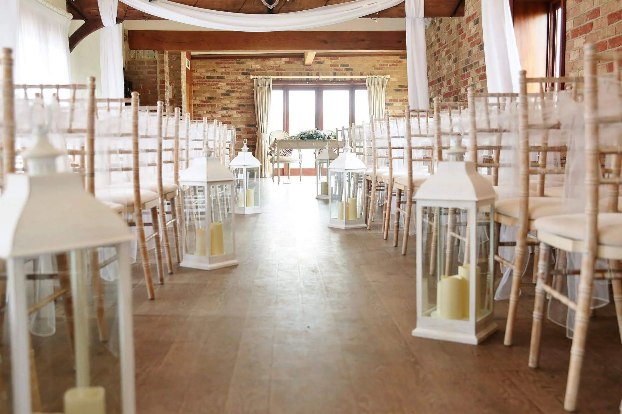 Cream LED Lantern Large placed along the aisle in a rustic wedding venue, available to hire for your wedding or event.