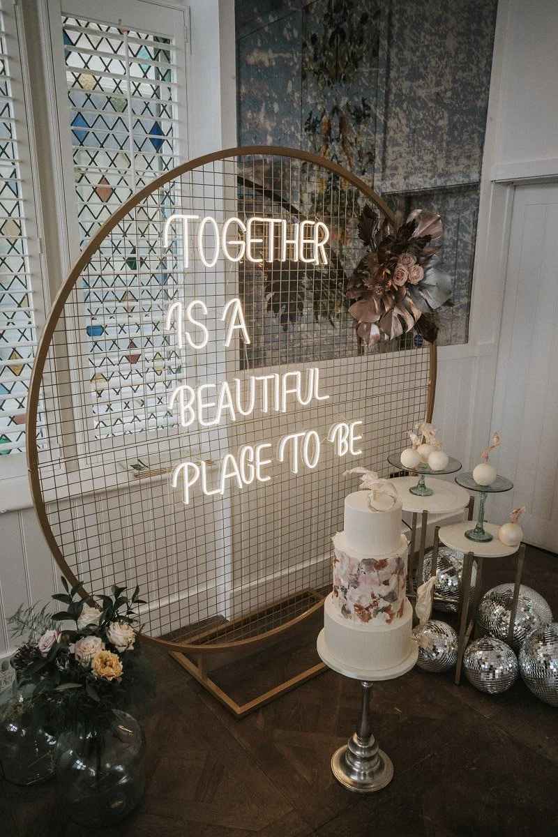 Mesh Circle Frame - Gold with neon sign and floral decoration, available to hire for your wedding or event.