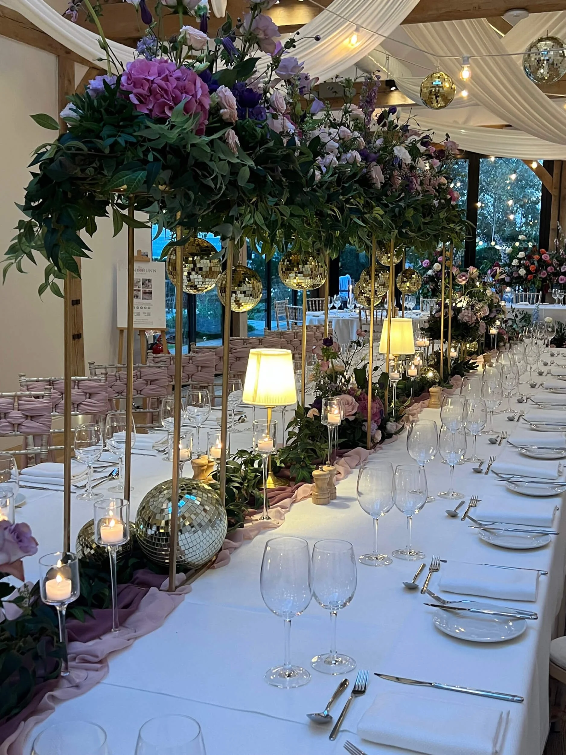 Gold Centrepiece Lamp with hanging gold disco balls and floral greenery, available to hire for your wedding or event.