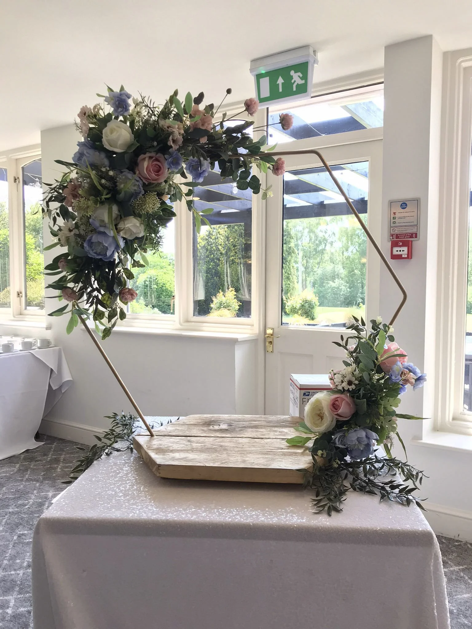 Gold Cake Stand - Hexagon - 80cm hoop, 45cm base decorated with pastel faux florals, available to hire for your wedding or event.
