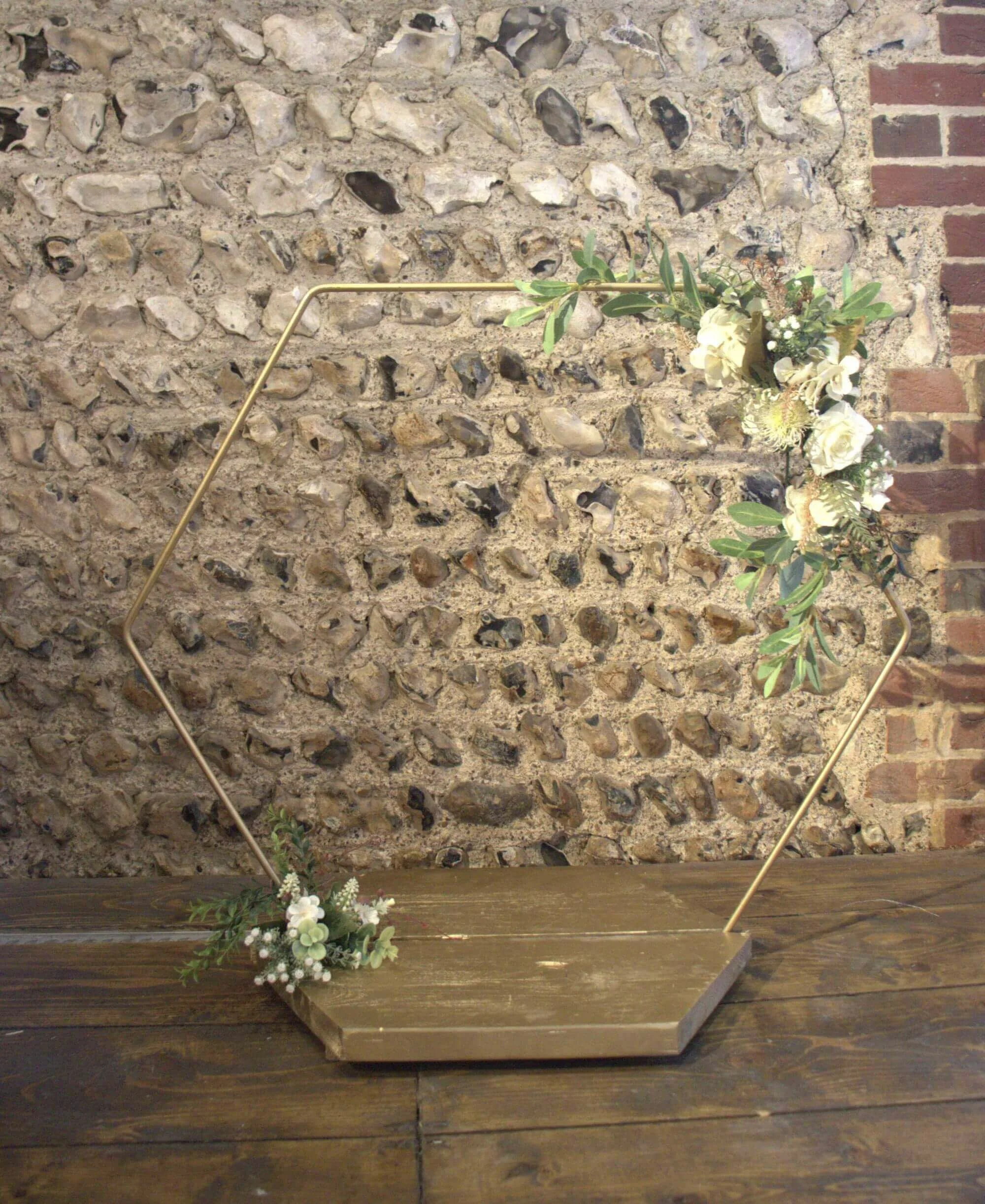 Gold Cake Stand - Hexagon - 80cm hoop, 45cm base decorated with faux white flowers and greenery, available to hire for your wedding or event.