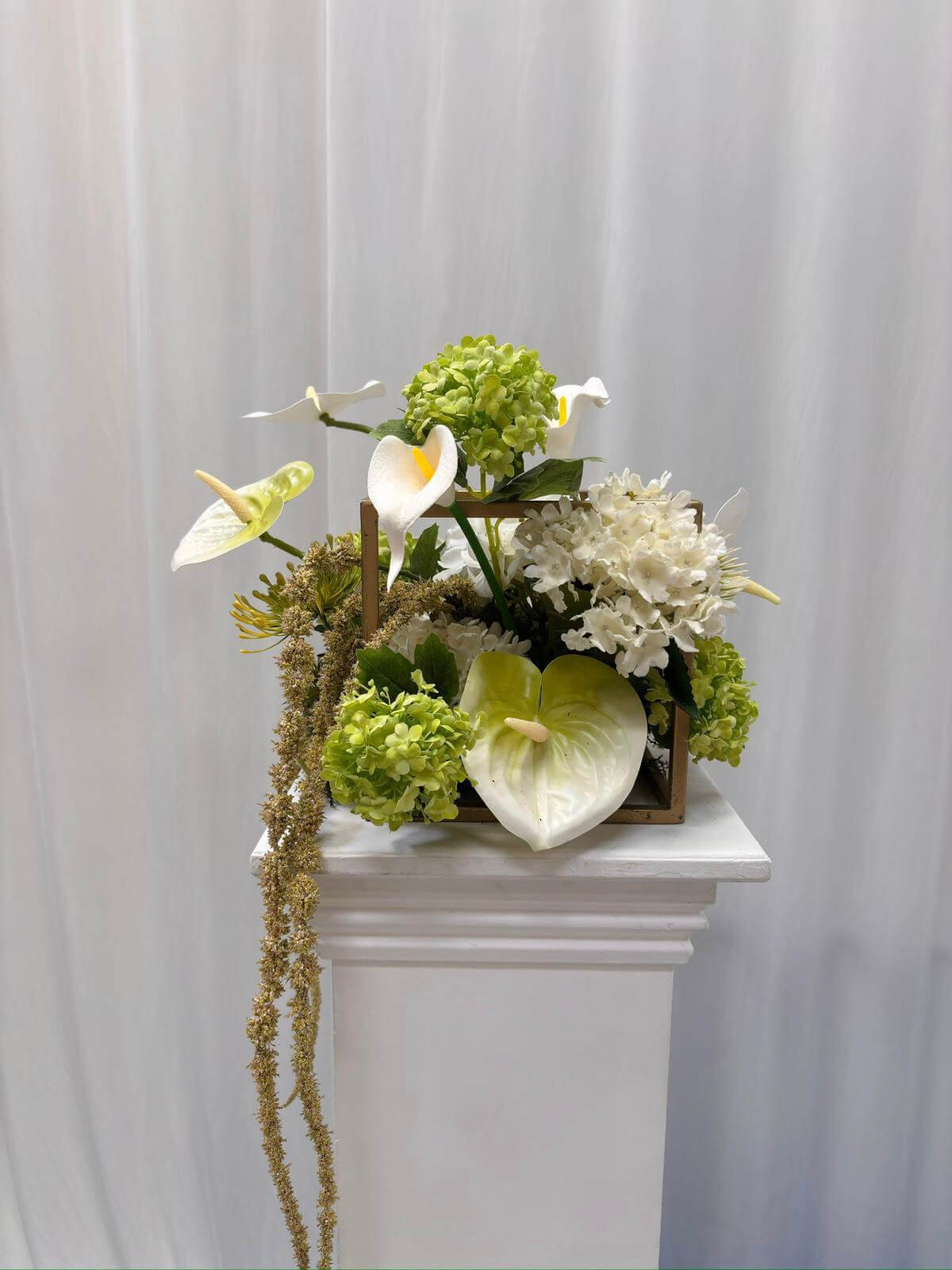 Pedestal Cube - Gold decorated with white and green faux flowers, available to hire for your wedding or event.