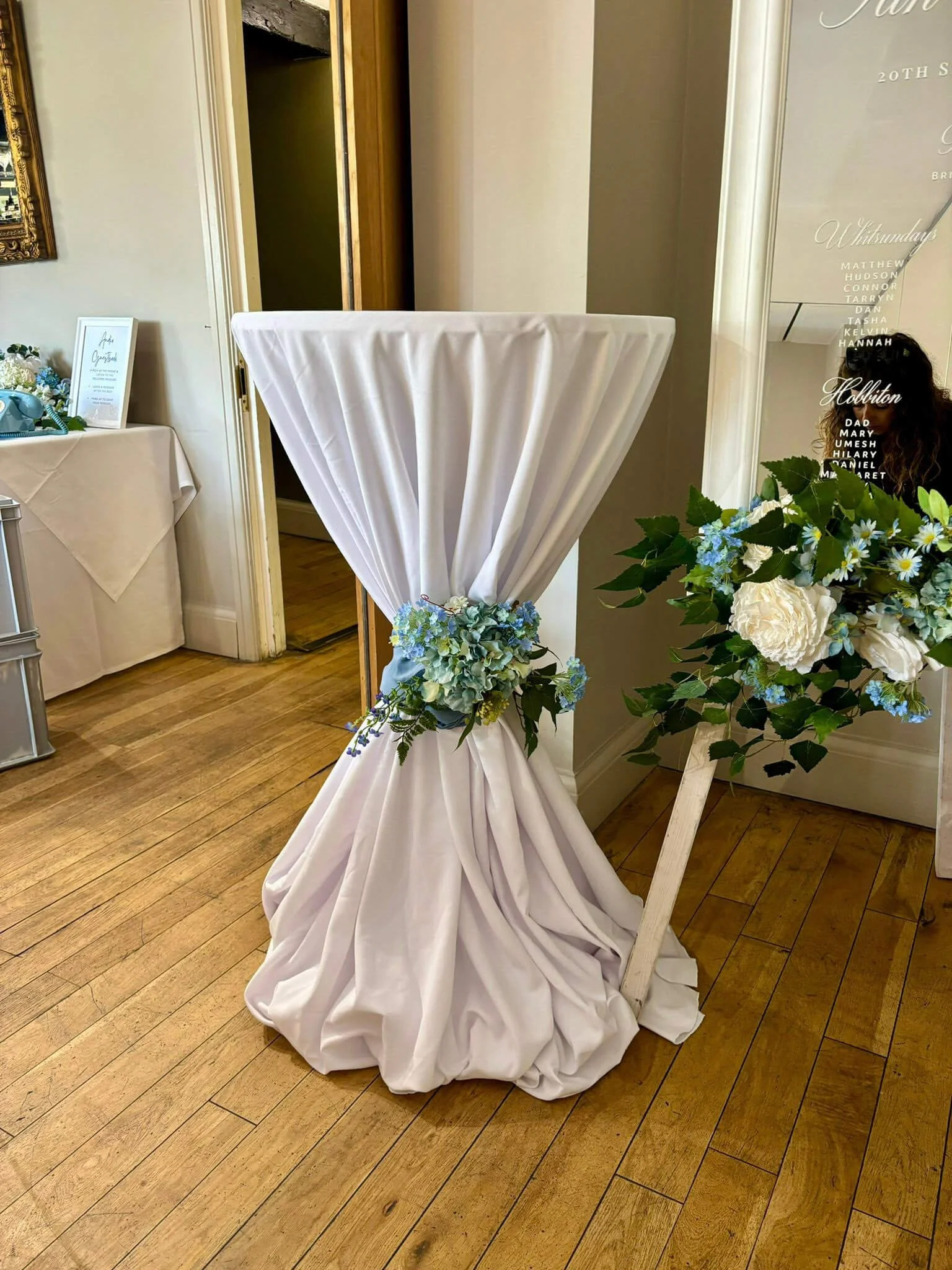 Poseur Table - Various Options styled as Poseur Table - tall table draped in white cloth with blue and green floral tie, available to hire for your wedding or event.