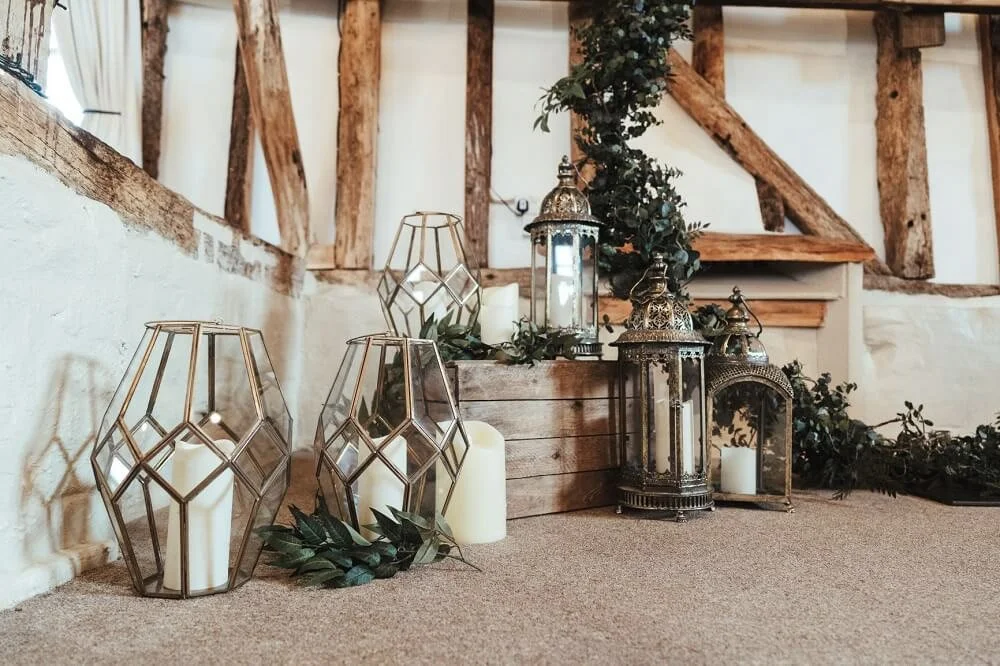 Mohani Lantern - Large ornate metal and glass lantern available to hire for your wedding or event, styled with candles and greenery indoors.