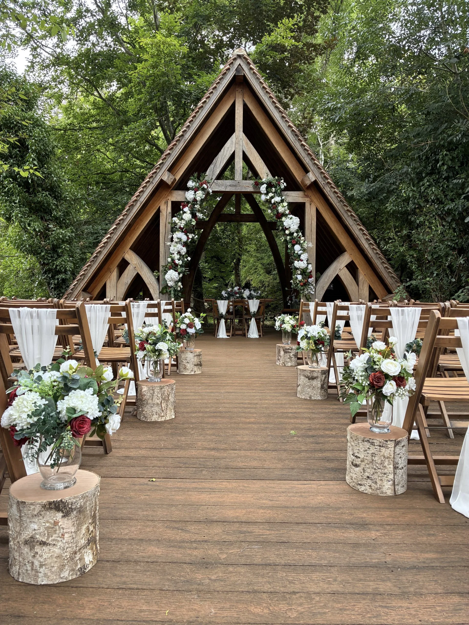 Raised Logs - Large used as natural wood stands with floral decorations along an aisle, available to hire for your wedding or event.