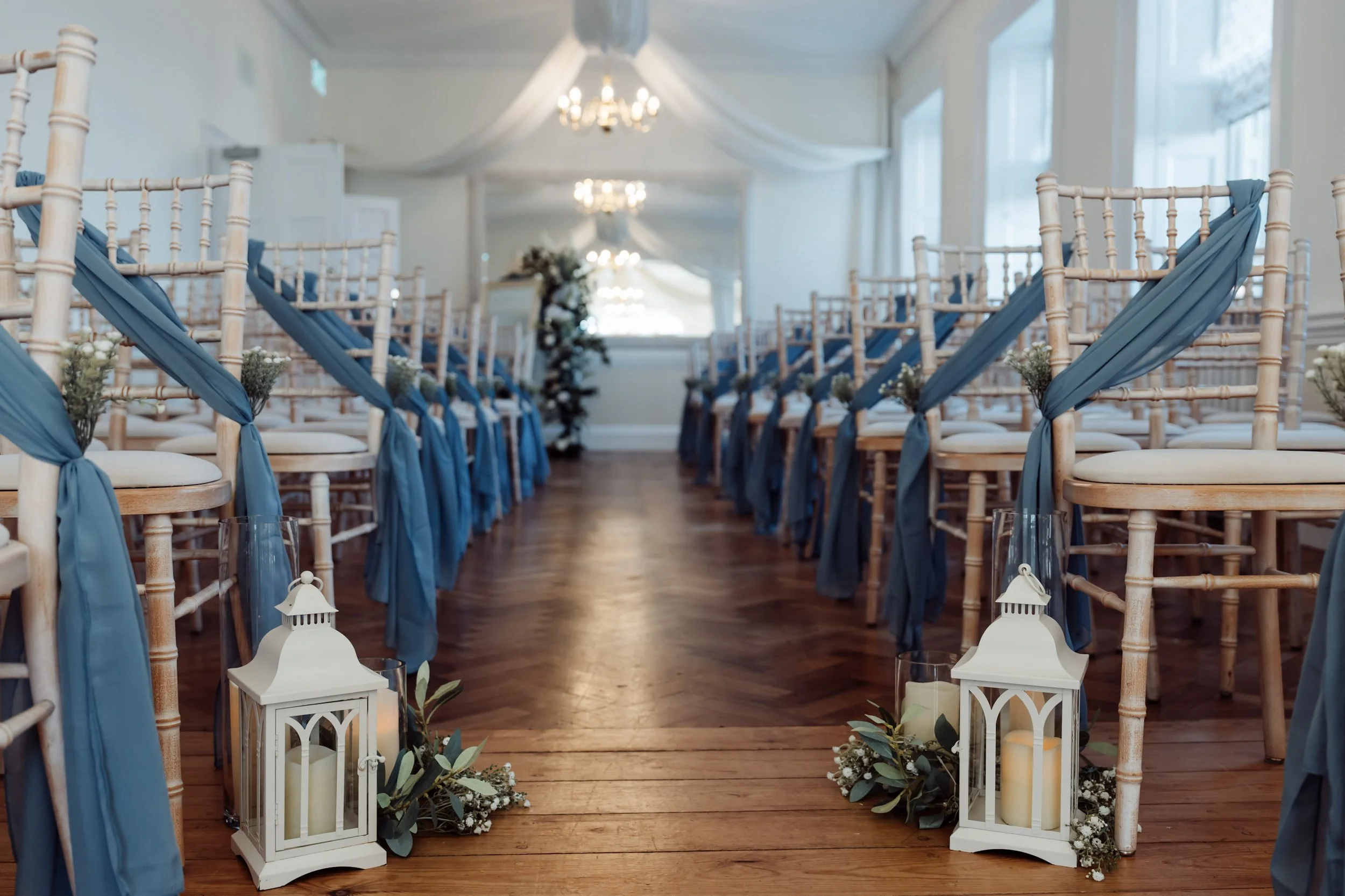 Cream Antique Lantern - Small placed along an aisle with blue fabric and greenery, available to hire for your wedding or event.