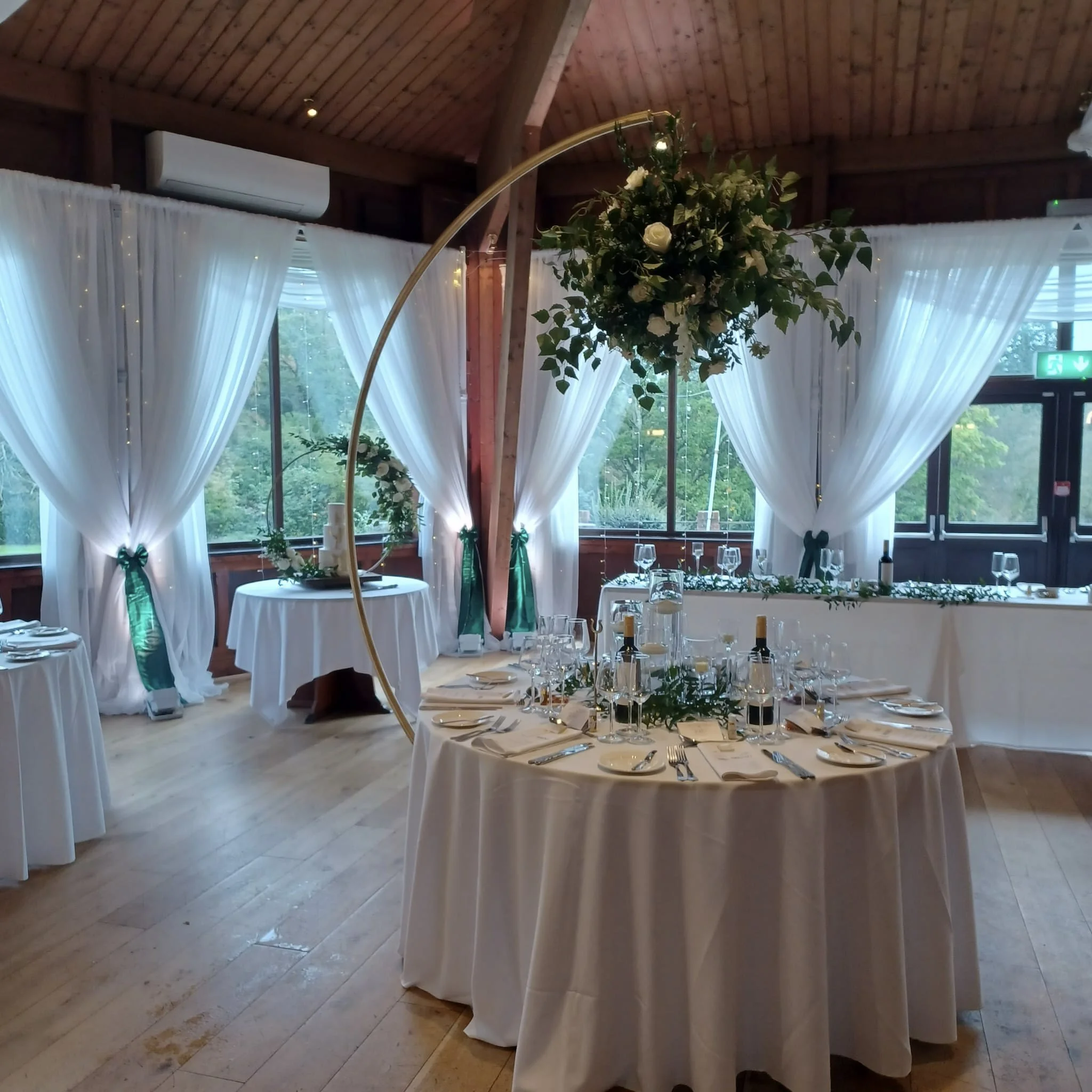 Half Moon Floral Stands Gold featuring white roses and greenery, available to hire for your wedding or event in an elegant indoor setting.