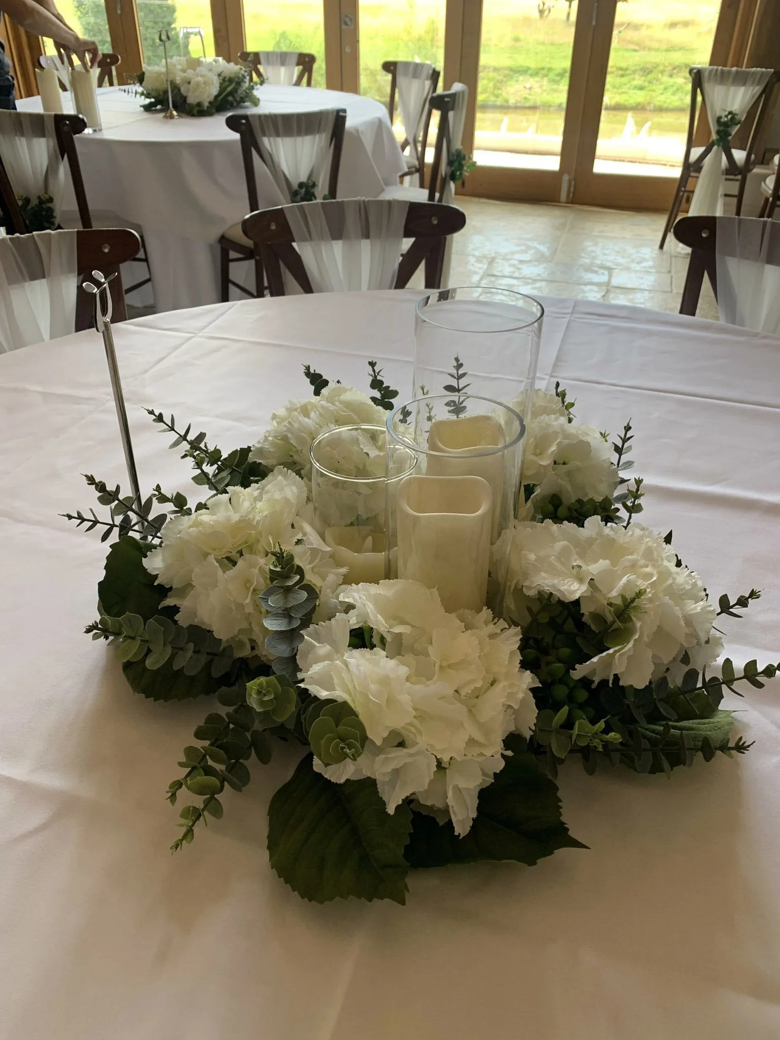 Hydrangea Faux Flower large Wreath with white flowers and greenery surrounding pillar candles, available to hire for your wedding or event.