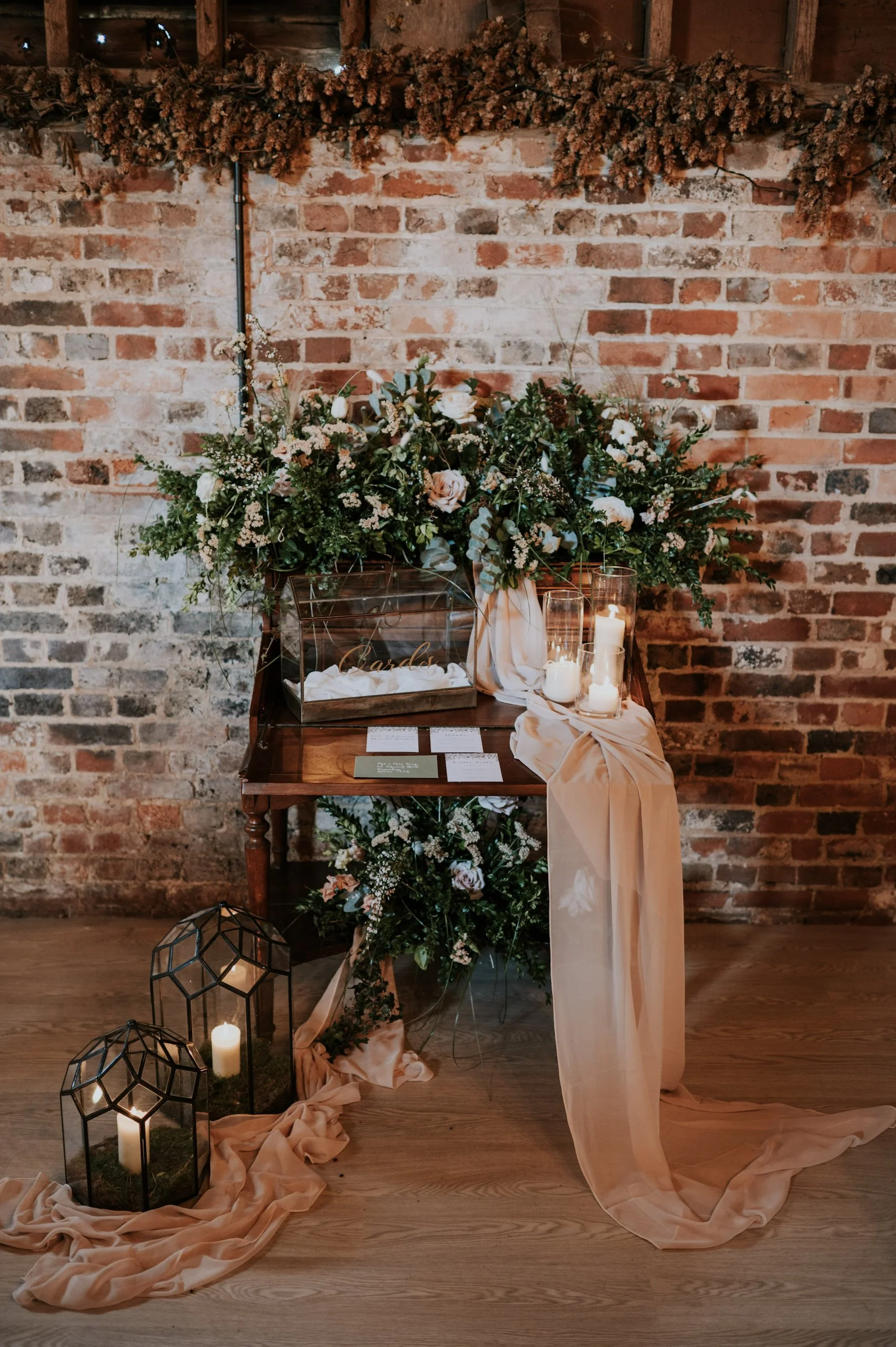 Antique Bureau with floral arrangements, candles, and draped fabric, available to hire for your wedding or event.