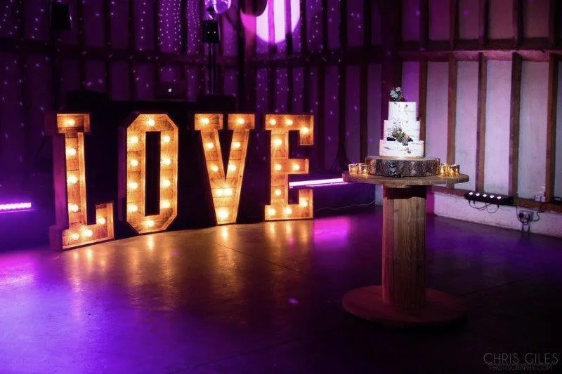 Giant Light Up Letters Rustic Love illuminated with warm bulbs in a rustic venue, available to hire for your wedding or event.