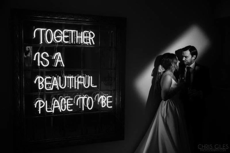 Together is a beautiful place to be Neon Sign in white neon light, available to hire for your wedding or event, shown with bride and groom in elegant setting.