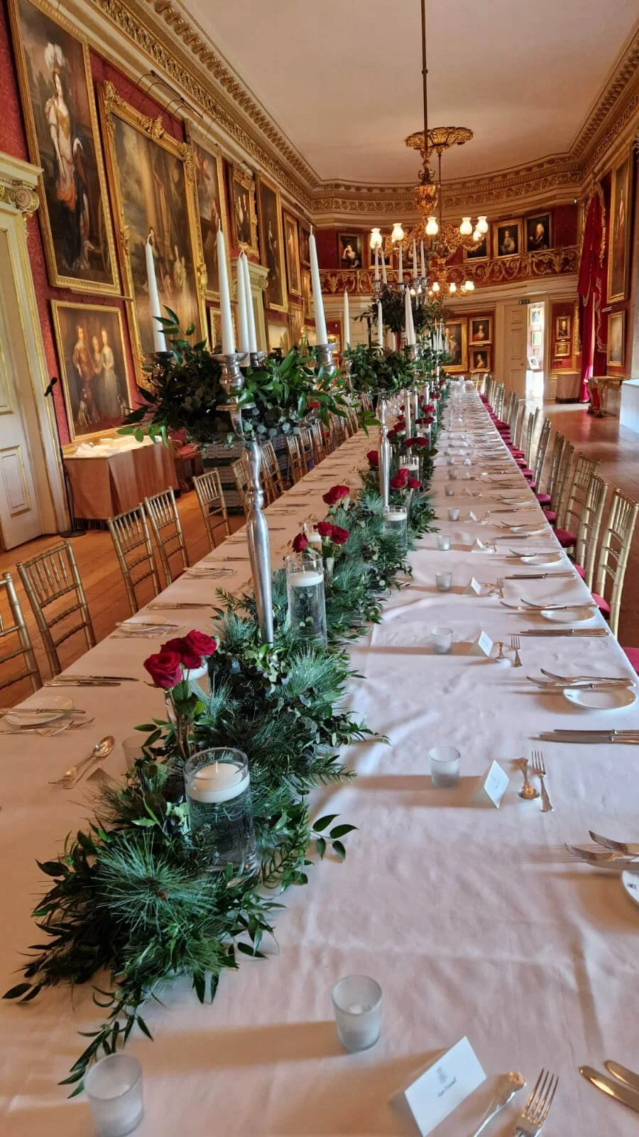 Candelabra Silver - 80cm with white taper candles and greenery centerpiece on long banquet table, available to hire for your wedding or event.