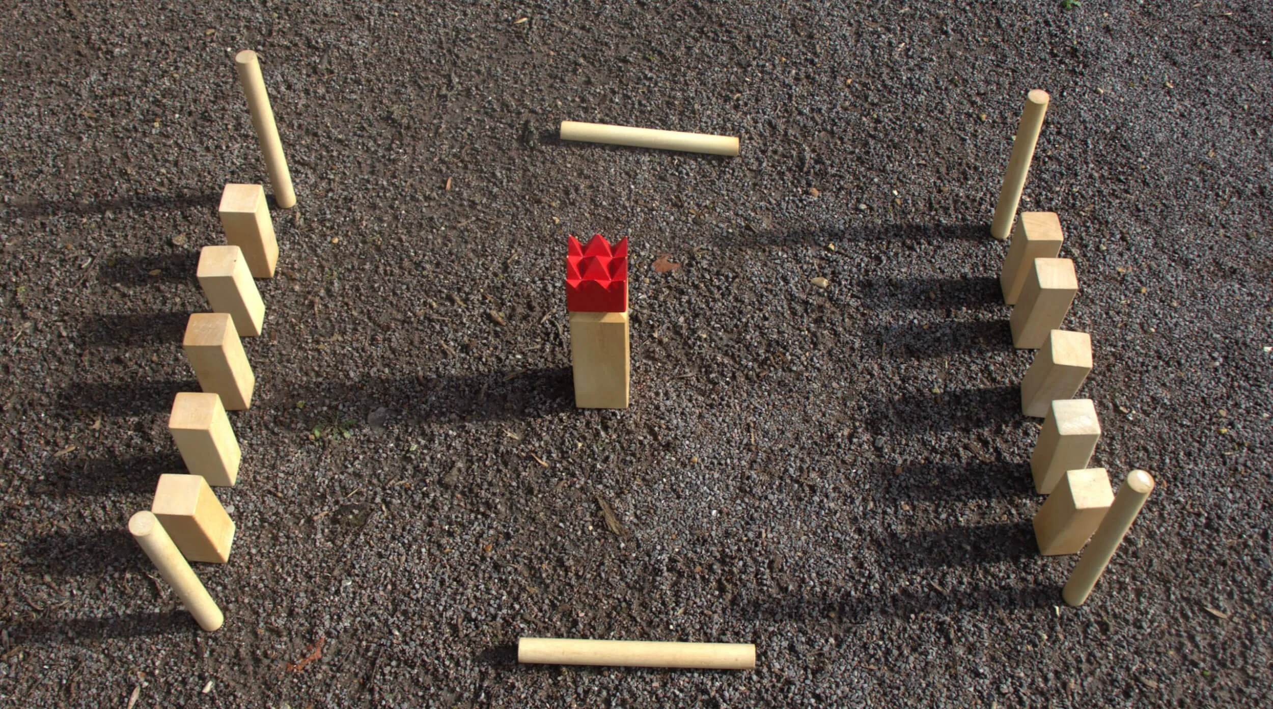 Kubb - Wooden game arranged on gravel with wooden blocks and batons, available to hire for your wedding or event.