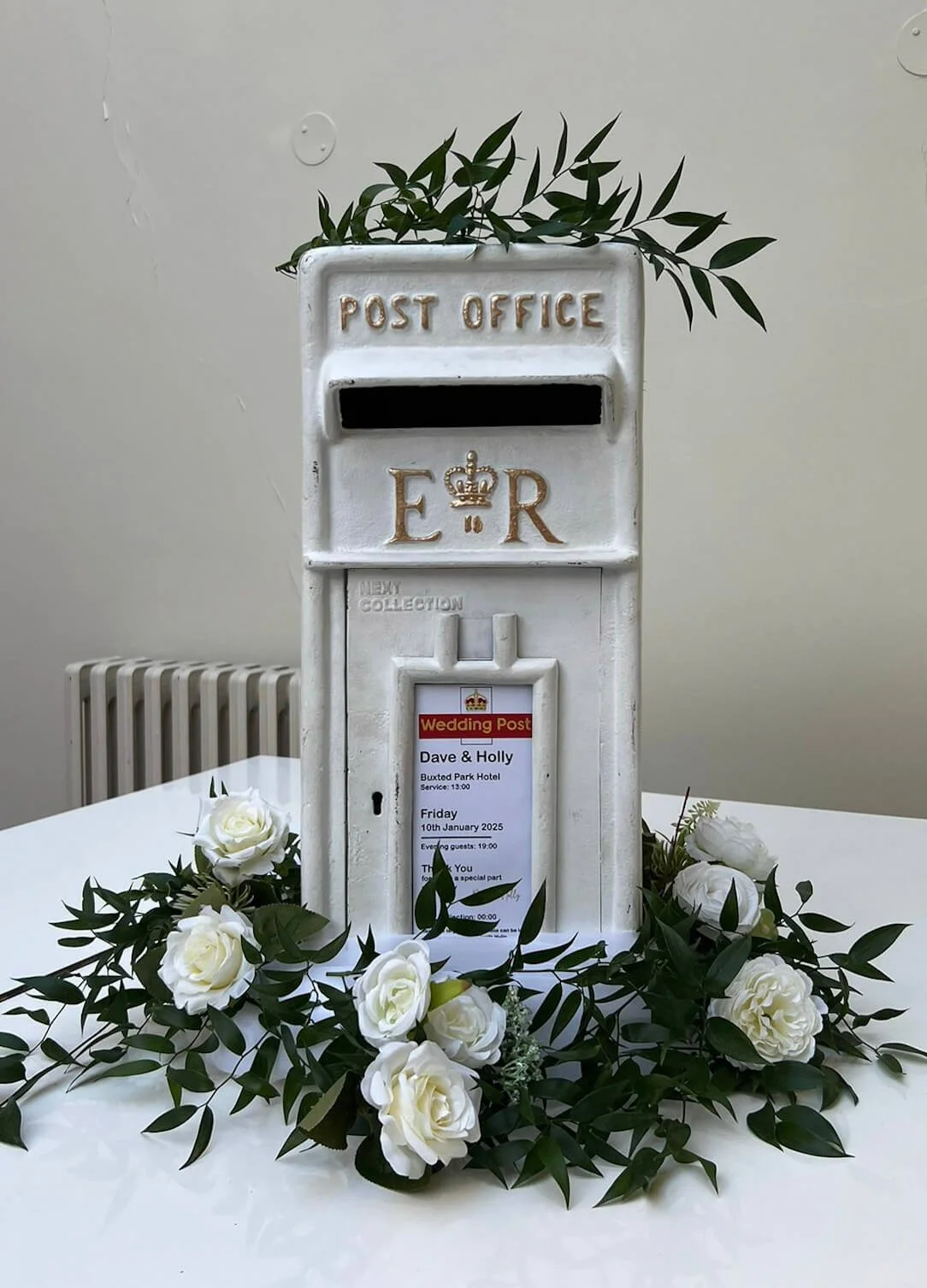 Royal Mail Post Box decorated with white roses and greenery, available to hire for your wedding or event.