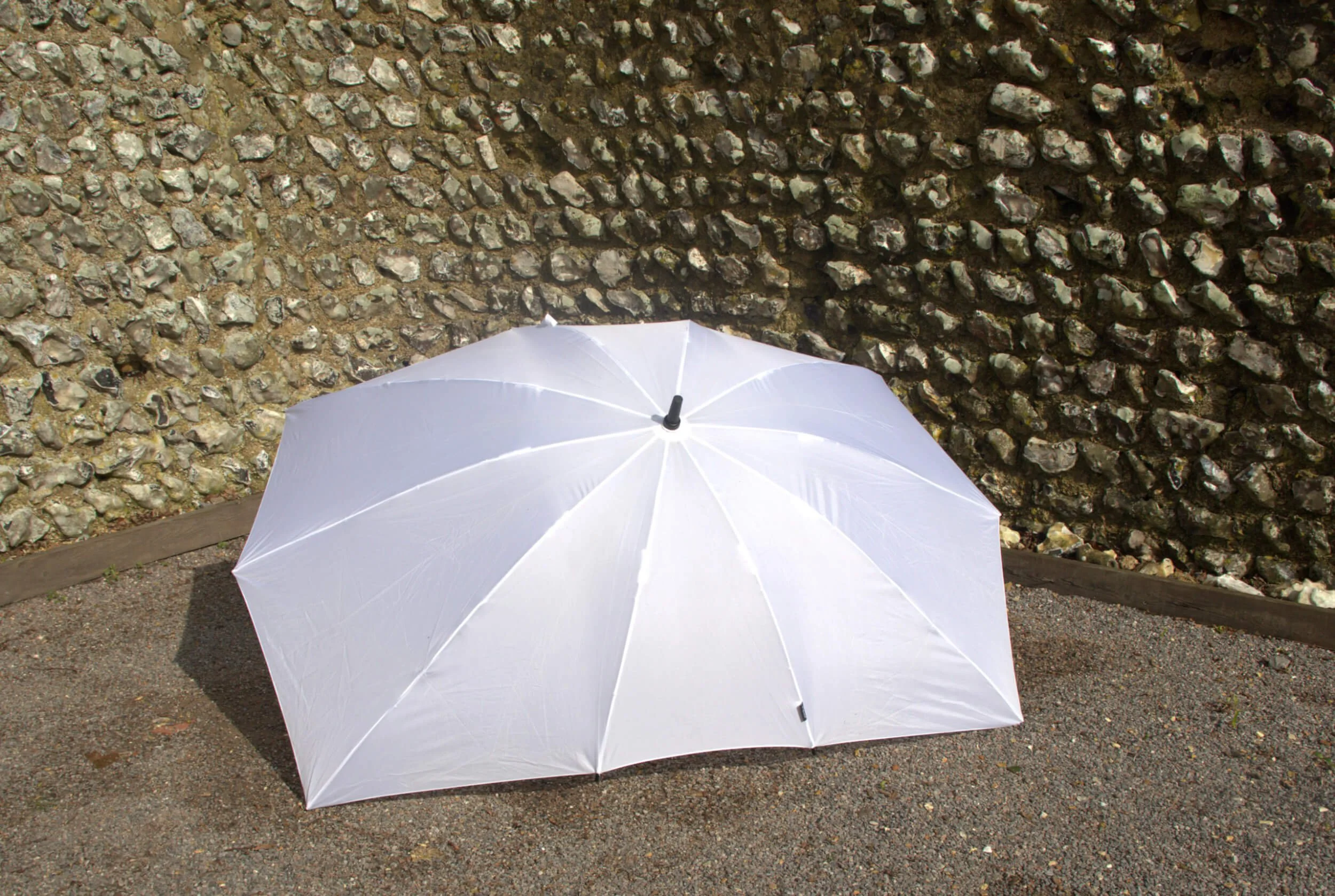 Twin Umbrella - White opened outdoors on gravel, available to hire for your wedding or event.