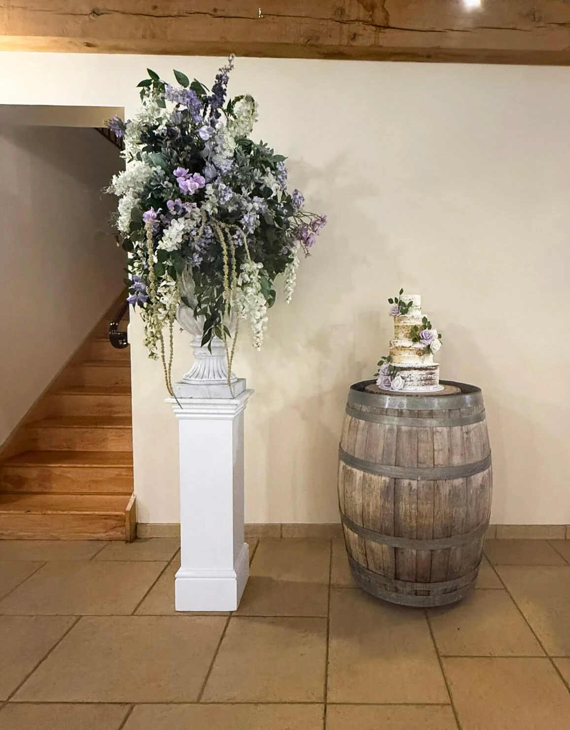Sussex Oak Cake Barrel with a three-tiered cake decorated with purple flowers, available to hire for your wedding or event.