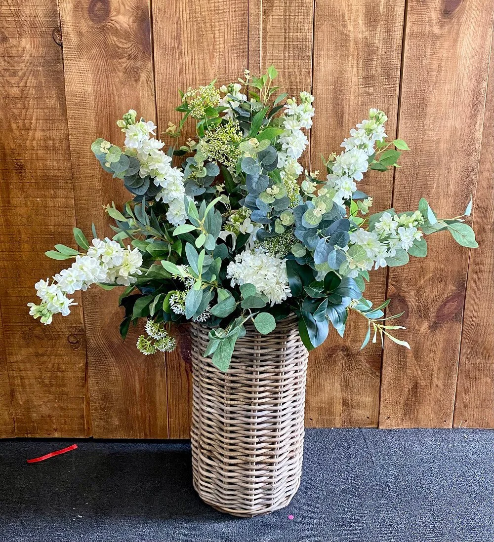 Wicker Foliage & Flower Display - Bespoke Colours featuring green foliage and white flowers in a tall wicker basket, available to hire for your wedding or event.
