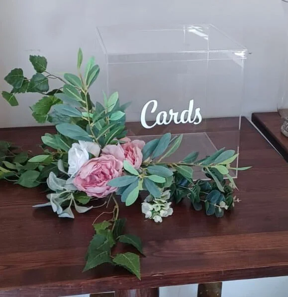 Clear Cards Post Box with floral decoration, available to hire for your wedding or event, displayed on a wooden table.
