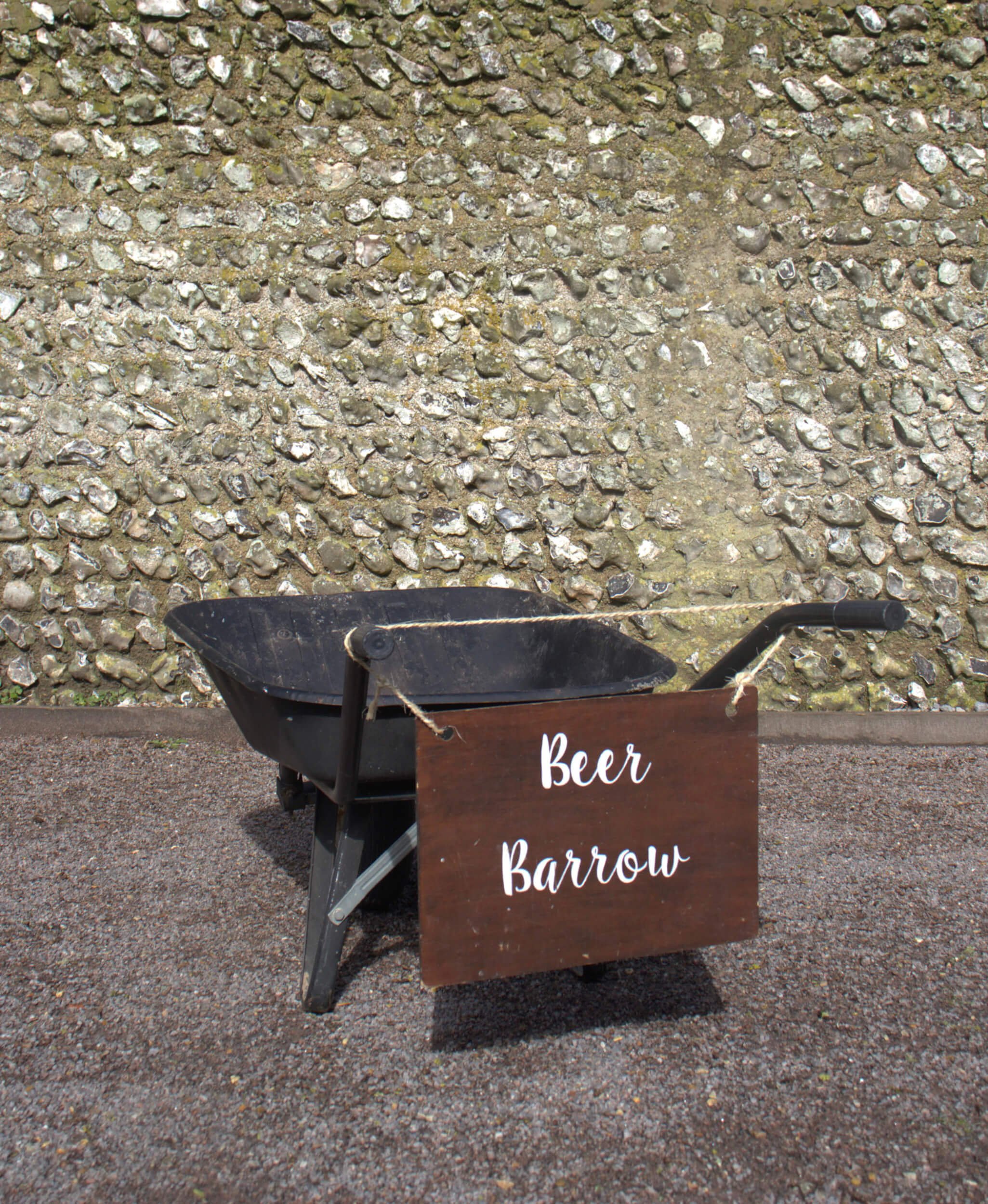 Beer Barrow with black metal wheelbarrow and wooden sign available to hire for your wedding or event.