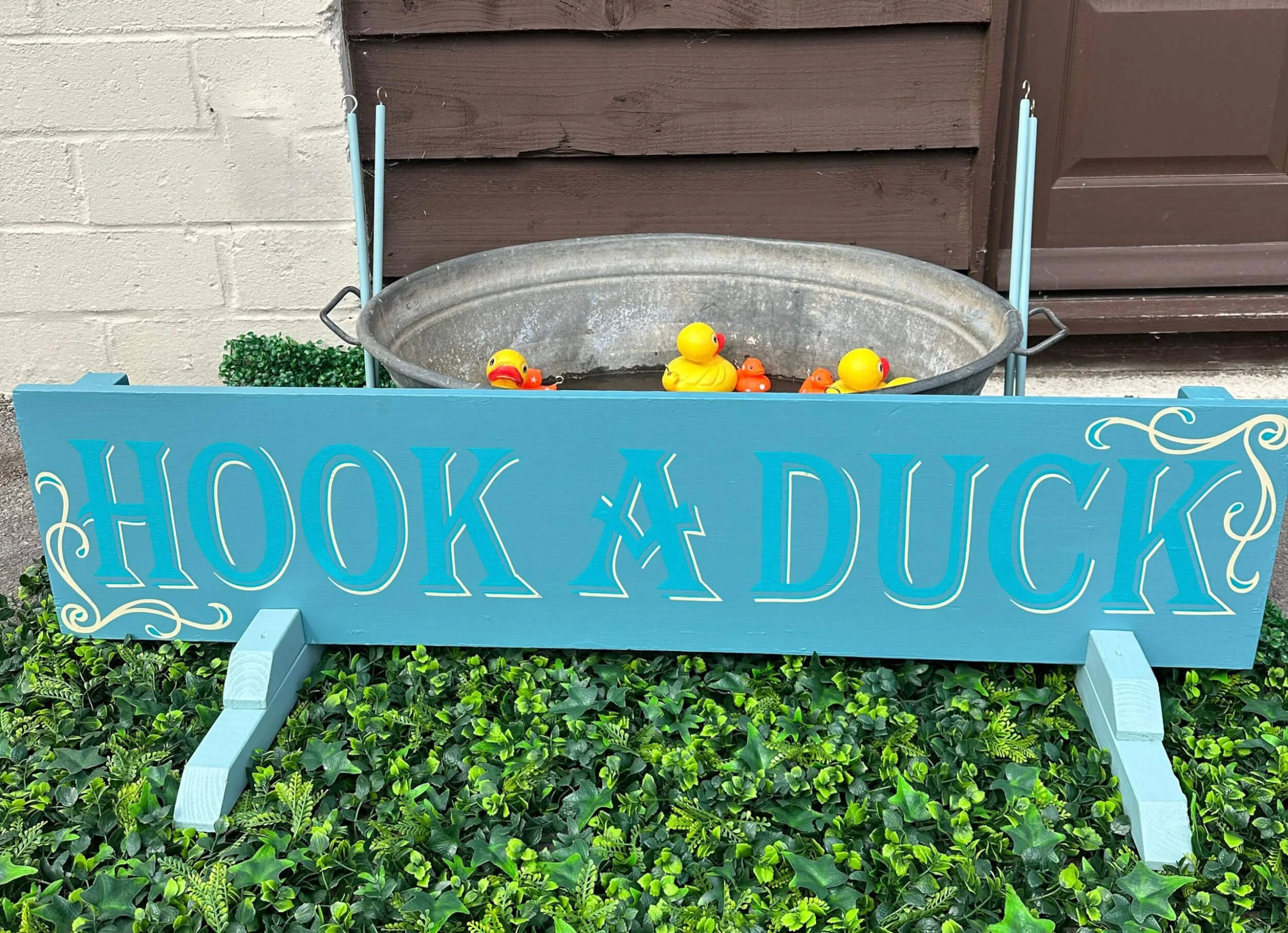 Hook a Duck game with a blue sign and metal tub with floating ducks, available to hire for your wedding or event.