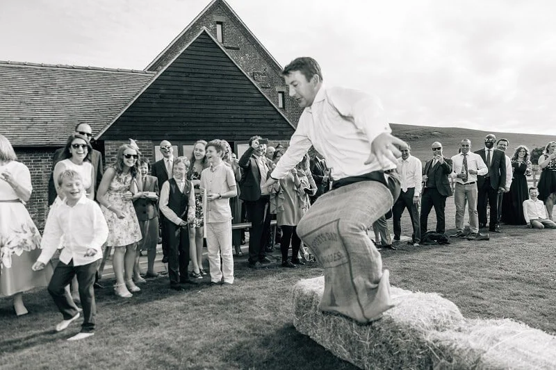 Sack Race SET OF 4 in use with a man jumping in a sack on grass, available to hire for your wedding or event with guests watching outdoors.