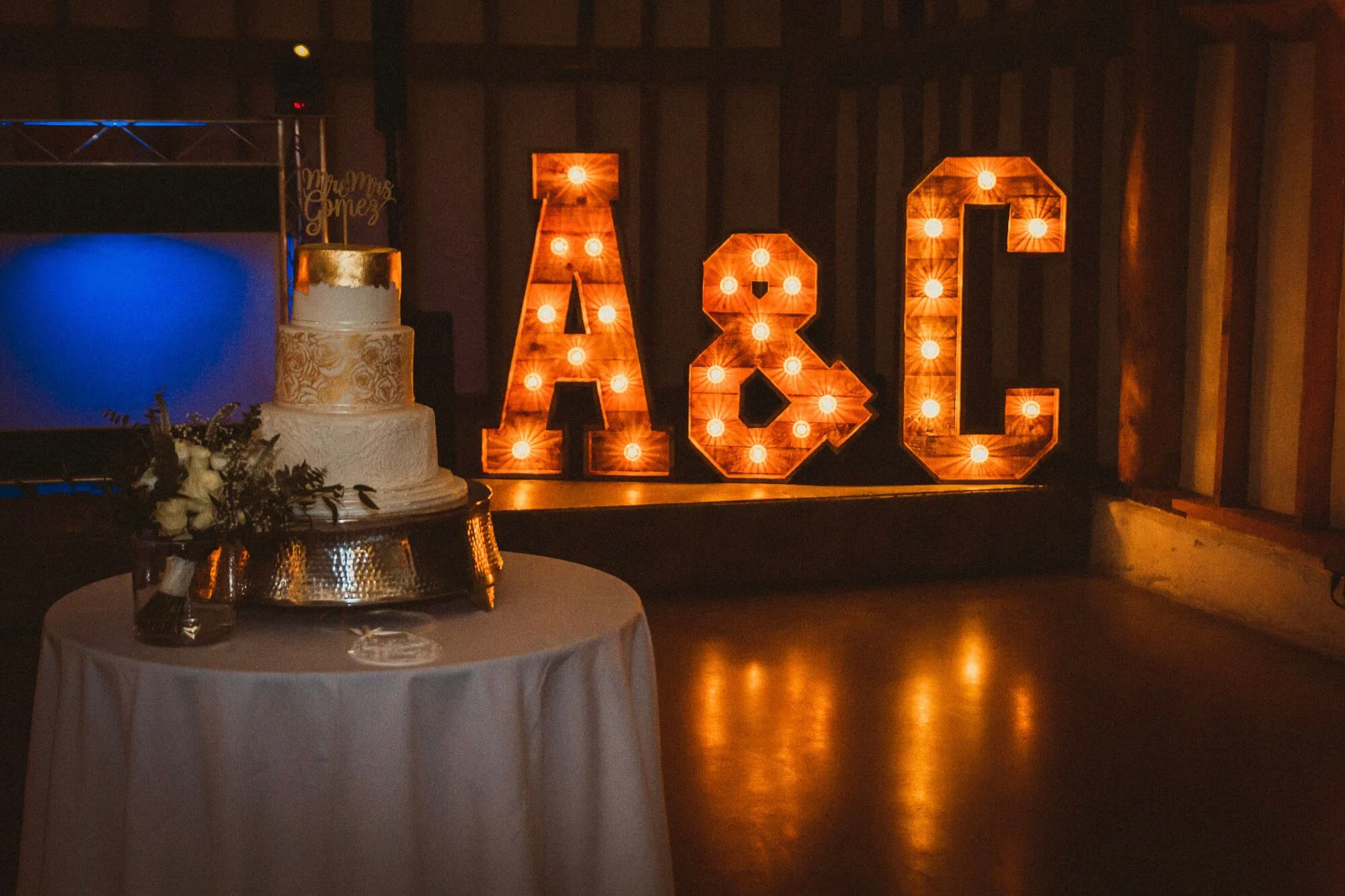 Giant Rustic Light Up Letters Initials*** styled as Giant Rustic Light Up Letters Initials illuminated with warm bulbs, displayed near a wedding cake, available to hire for your wedding or event.