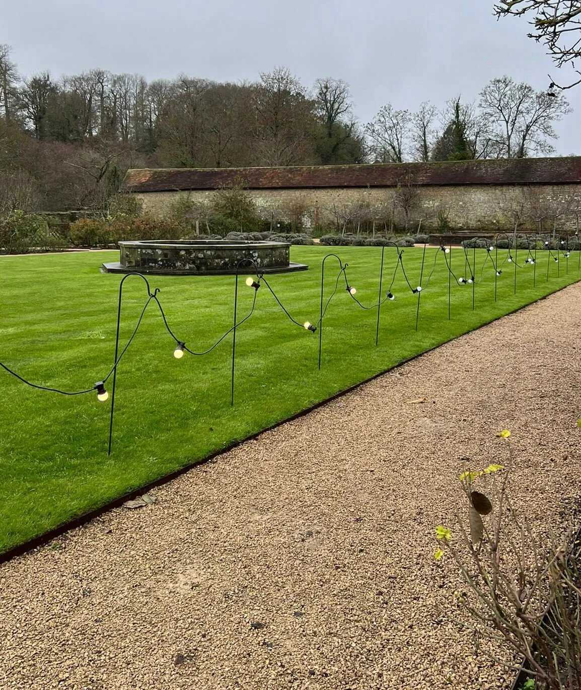 Shepherd Hooks - 1.2 metr holding string lights along a gravel path on grass, available to hire for your wedding or event.