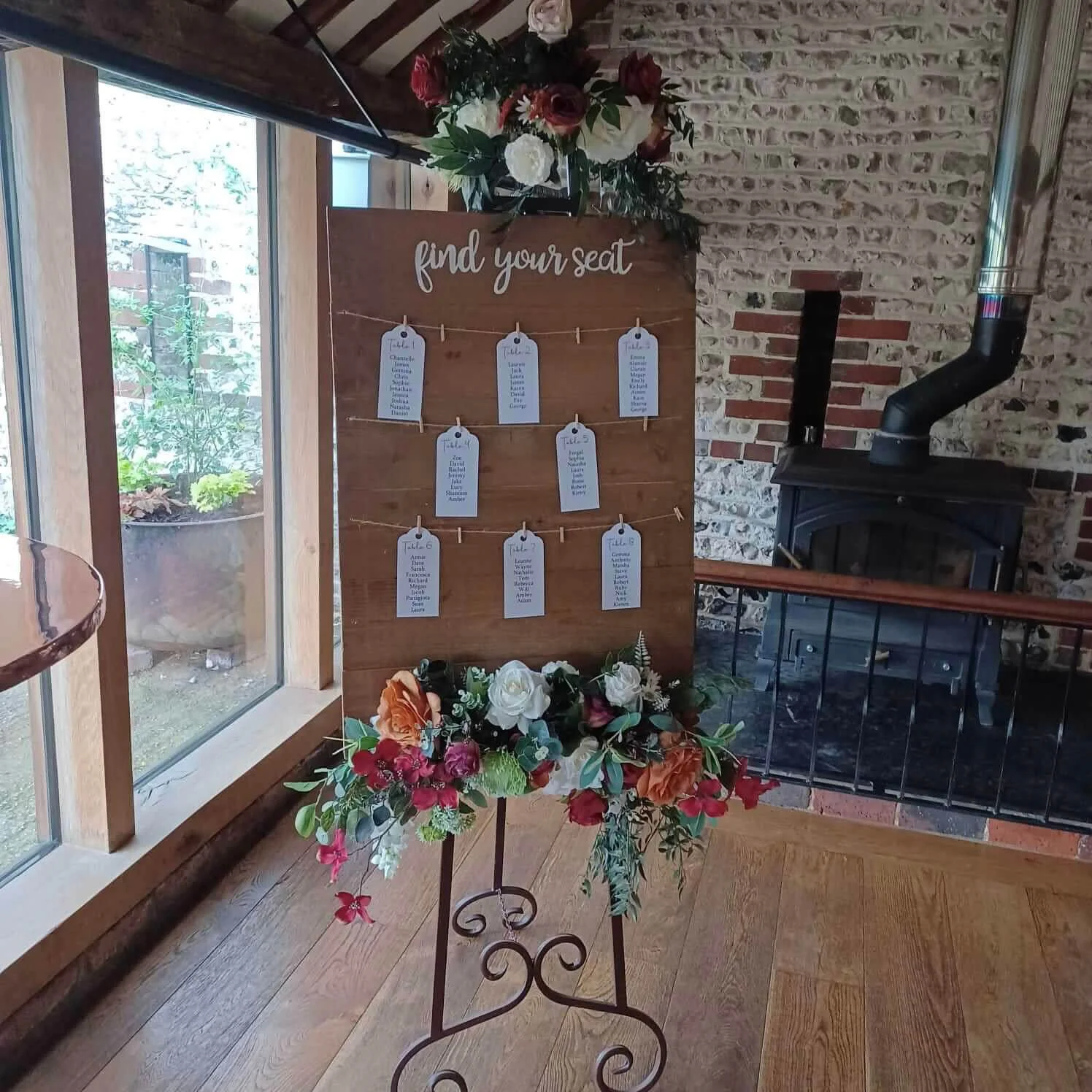 Find Your Seat Rustic Wooden Tableplan with hanging white tags and floral decorations, available to hire for your wedding or event.