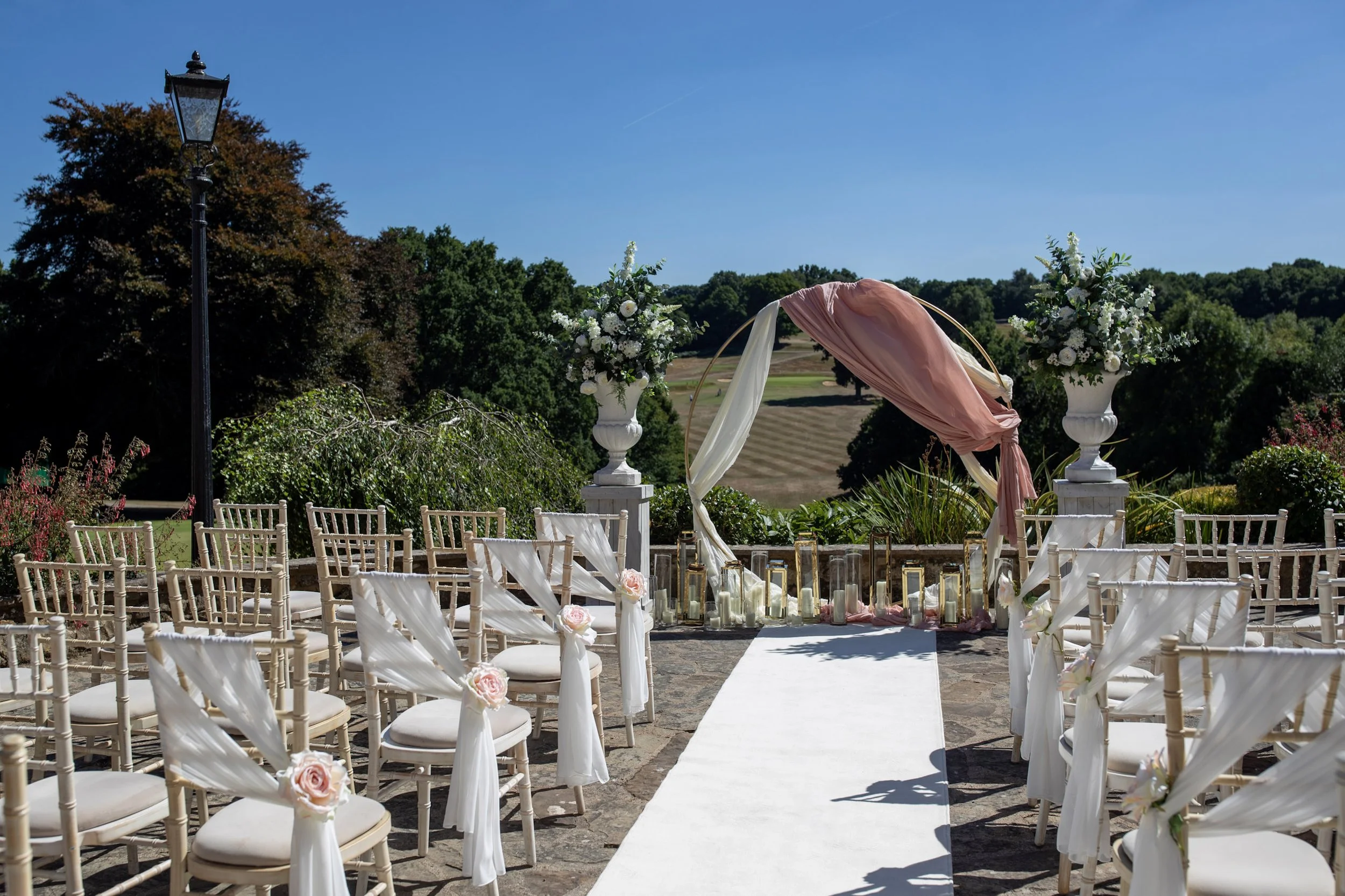 Aisle Runner - Cream Outdoor Use - Regular 10m x 1m laid on stone floor between decorated chairs in outdoor wedding setting, available to hire for your wedding or event.
