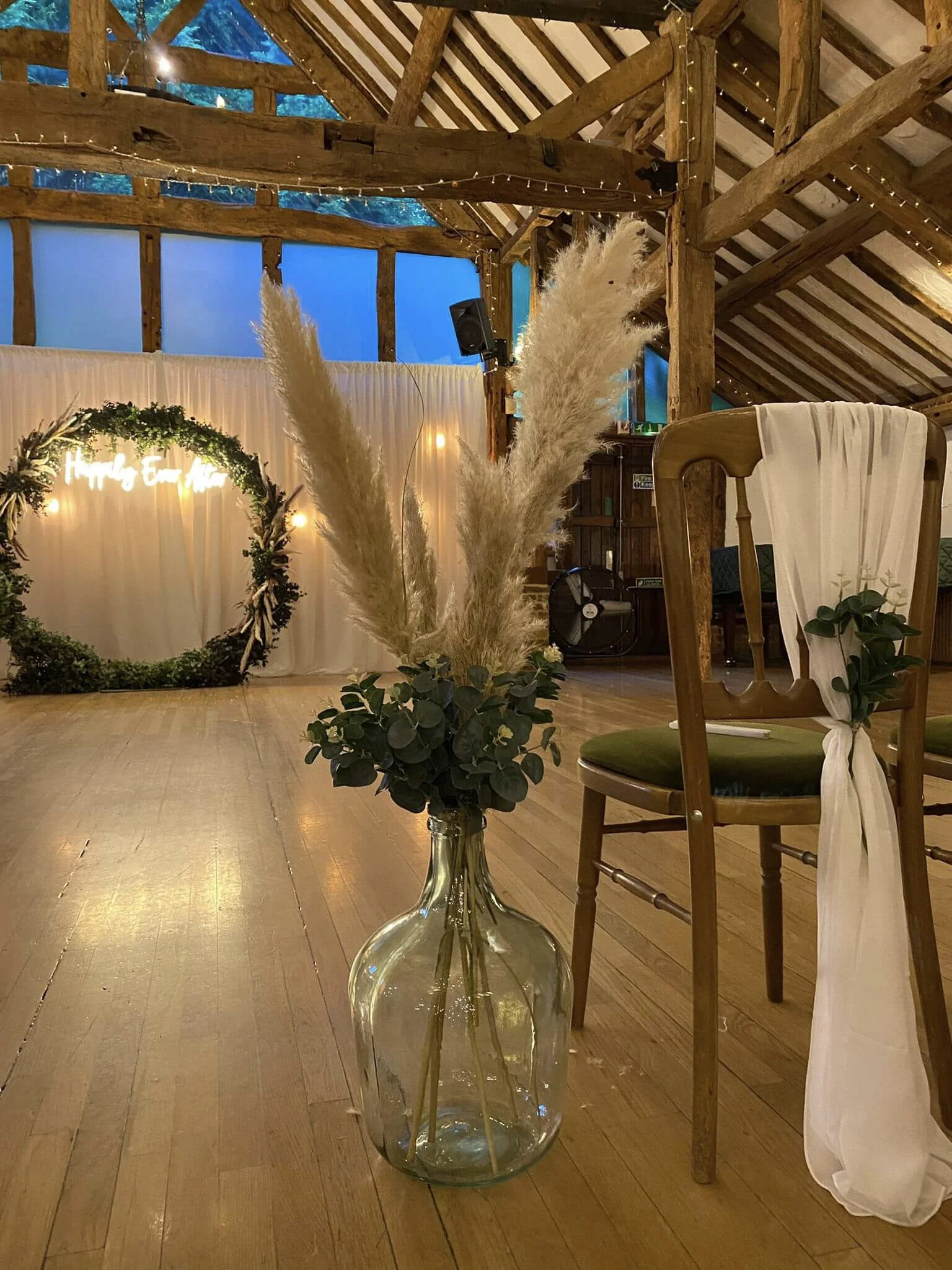 Giant Recycled Glass Bottle - 42cm x 27cm - opening at top 5cm diameter filled with pampas grass and greenery, available to hire for your wedding or event.