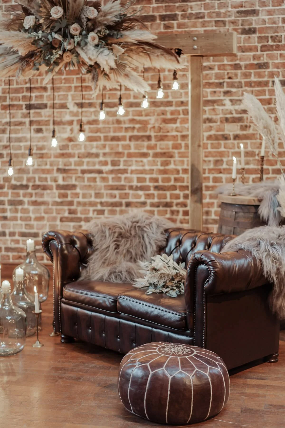 Sheepskin Rugs draped over a brown leather sofa in a rustic setting, available to hire for your wedding or event.