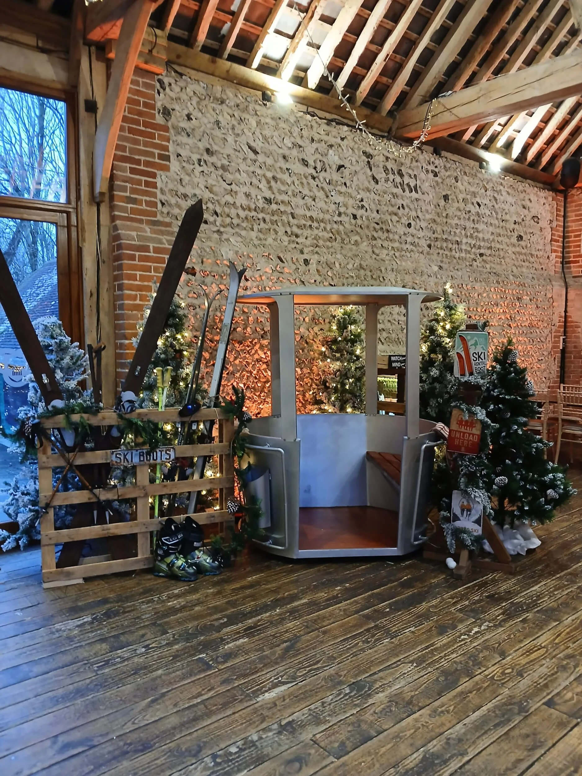Cable Car silver cabin in rustic indoor setting with skis and decorated Christmas trees, available to hire for your wedding or event.