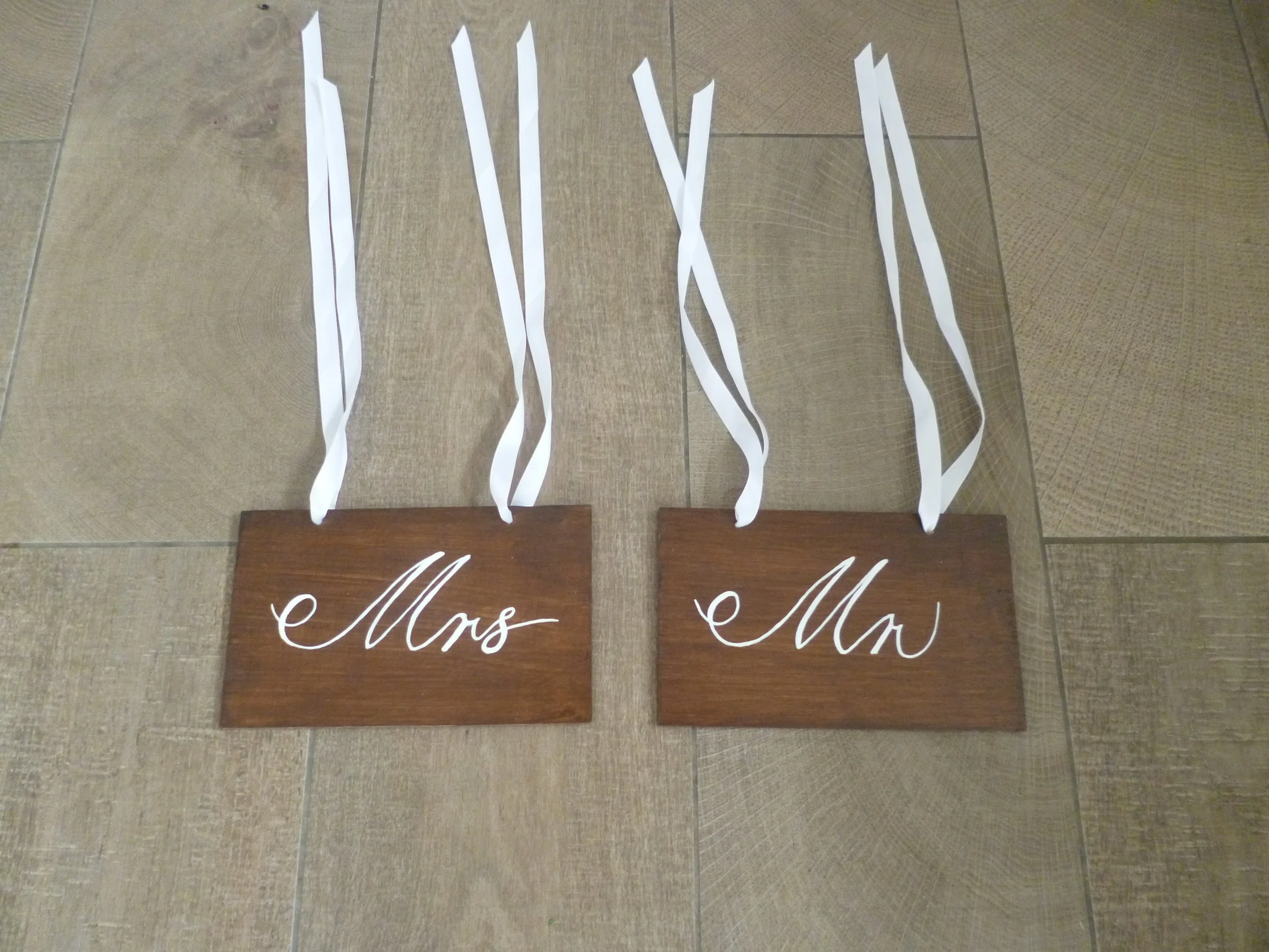 Wooden Mr & Mrs Chair Sign with white cursive text and ribbons, available to hire for your wedding or event.