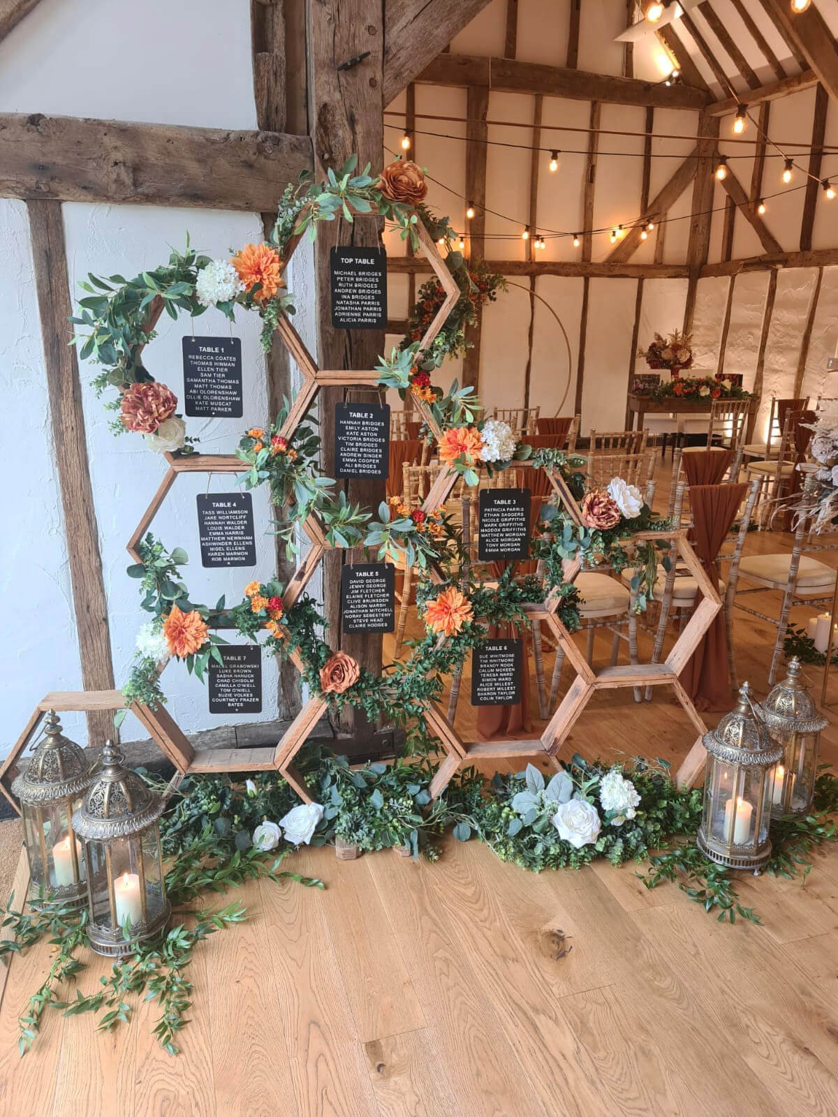 Hexagonal Tableplan decorated with faux greenery and flowers, available to hire for your wedding or event in a rustic indoor setting.